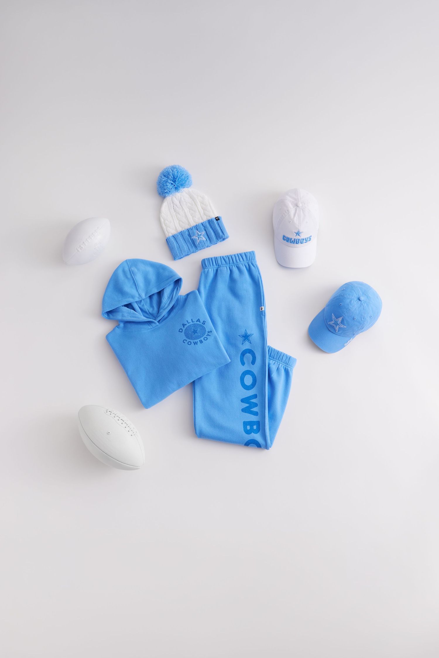 Light blue sportswear set with white baseball cap and pom beanie displayed on white background.