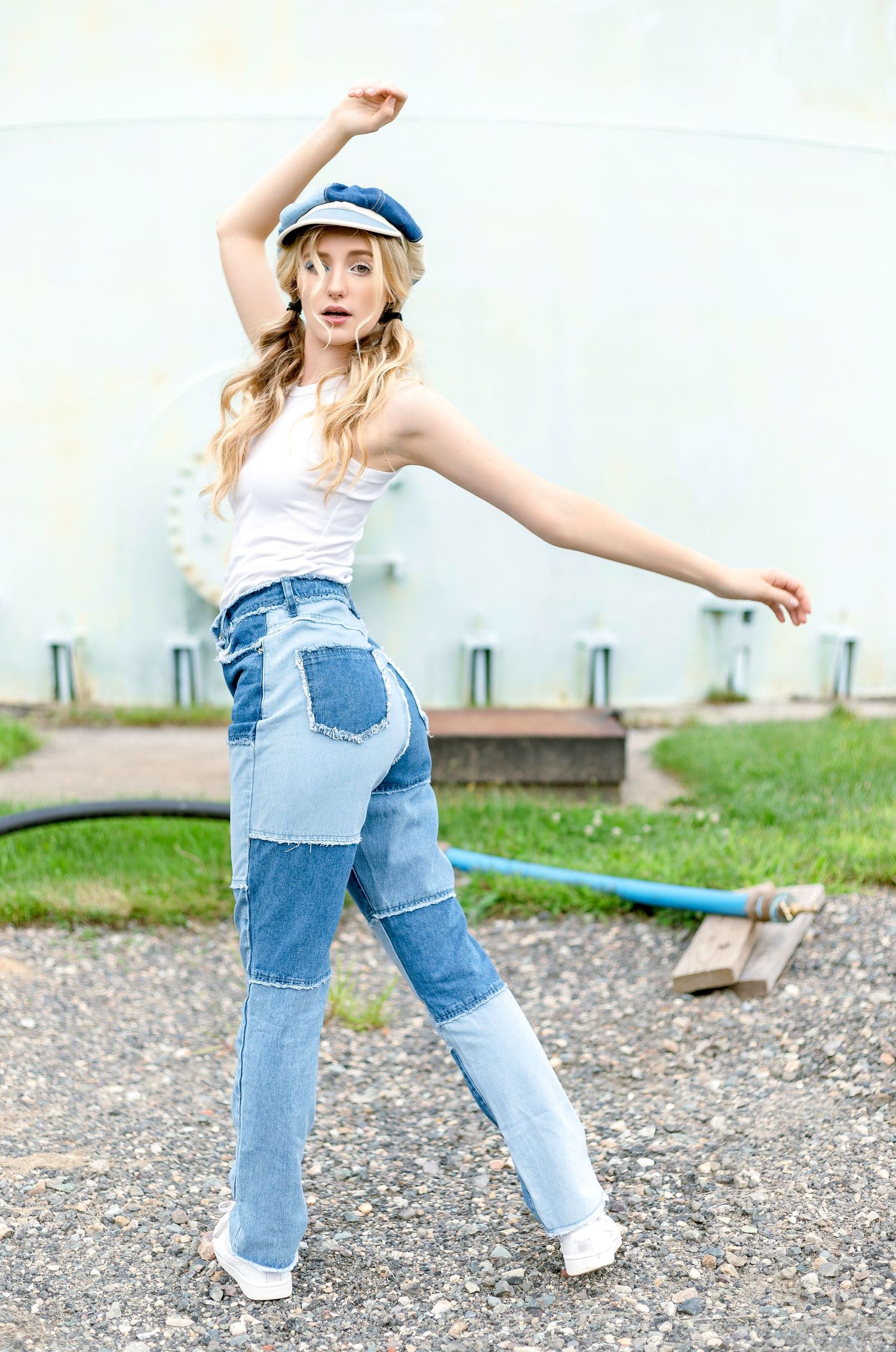 A dancer in patchwork denim overalls and sailor cap strikes dynamic poses in an outdoor setting.