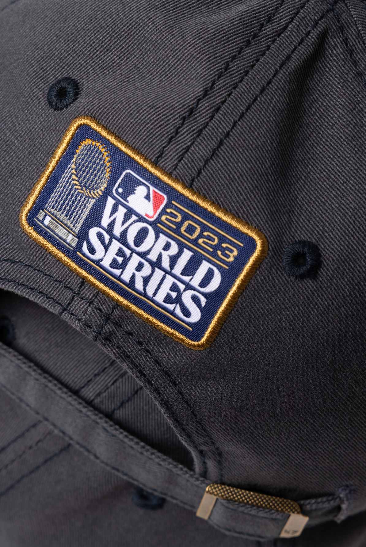Close-up detail of a black baseball cap showing the 2023 World Series championship patch with gold and navy accents.