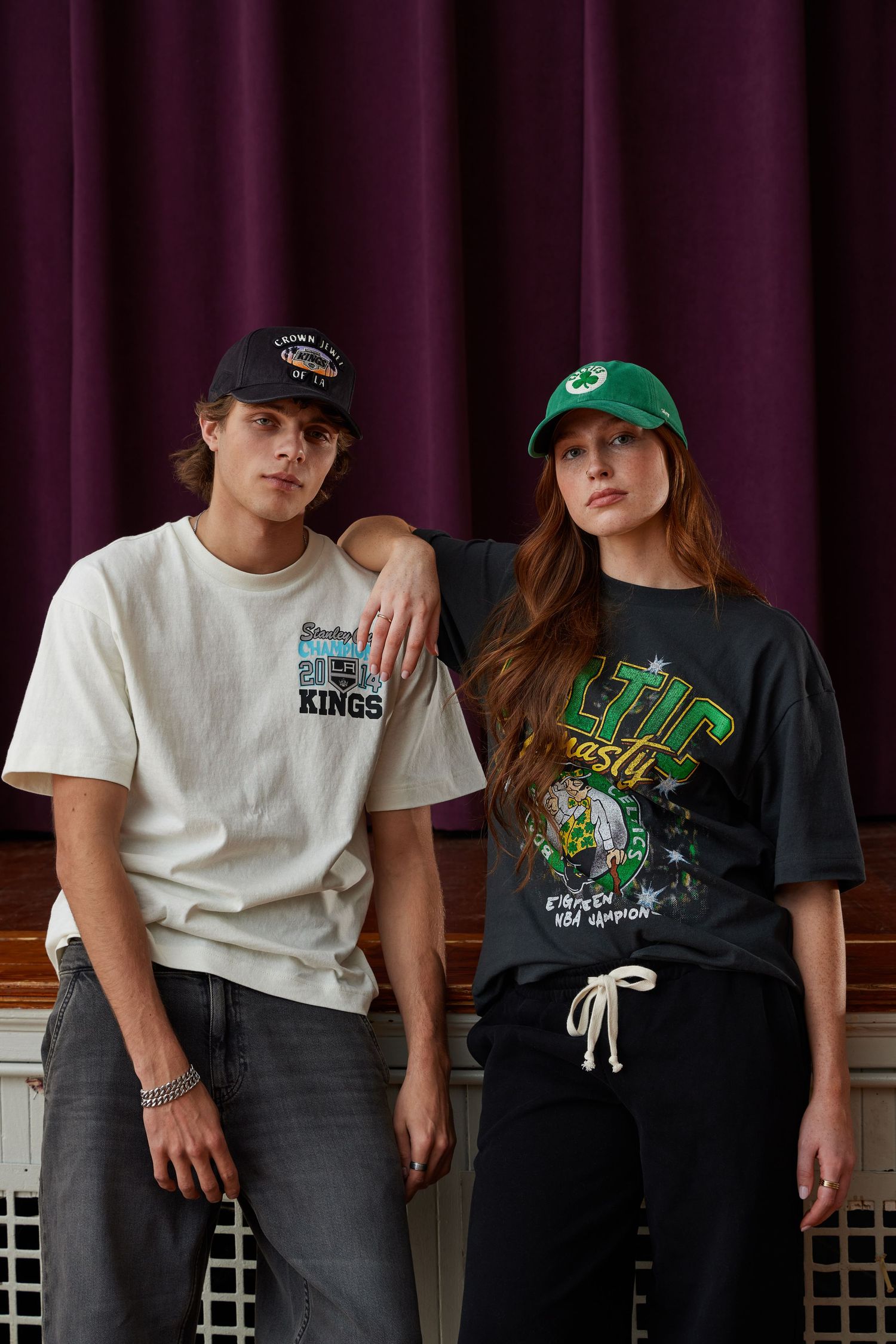 Row of people wearing casual t-shirts and jeans sitting against a dark wall with purple lighting.