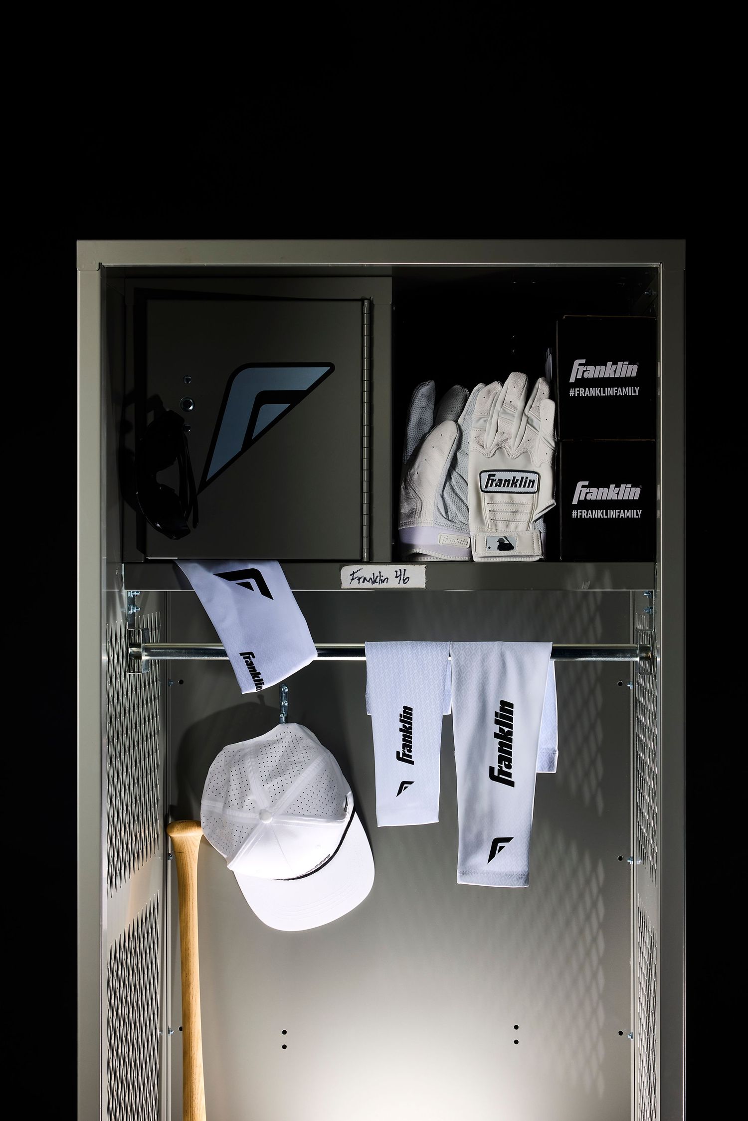 Baseball caps and gloves displayed on a white closet rod with Franklin branding visible in low light conditions.