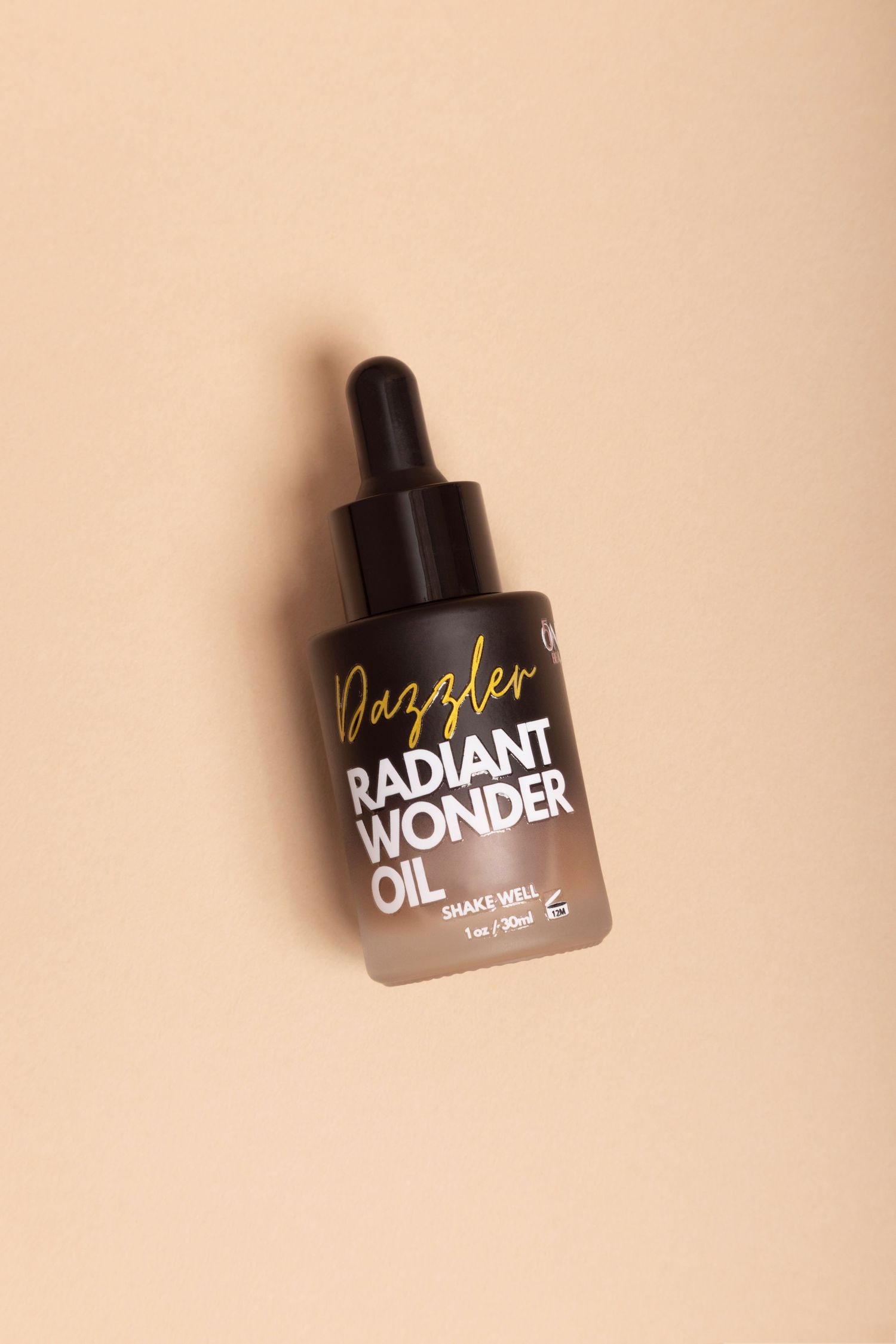 Three dark glass dropper bottles with beauty product labels against a beige background.