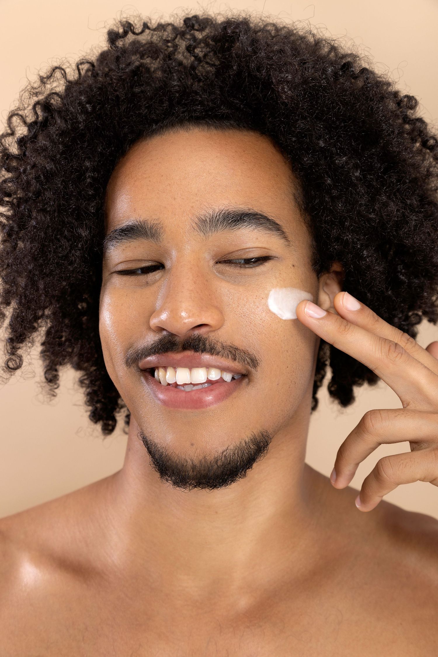 A person with curly natural hair and glowing skin applies moisturizer in a skincare routine progression.