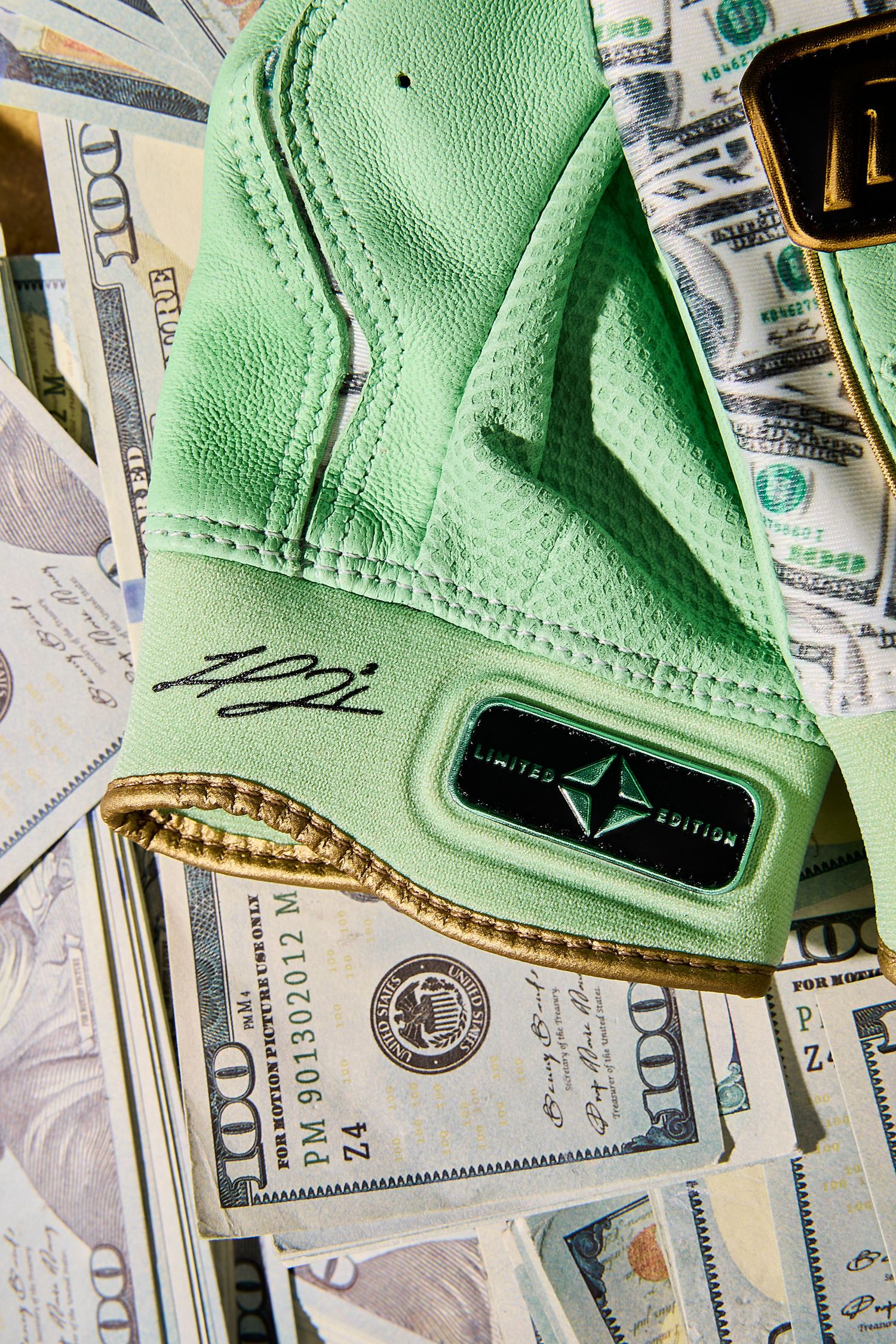 A mint green golf glove rests on a spread of US dollar bills showing financial success in golf.