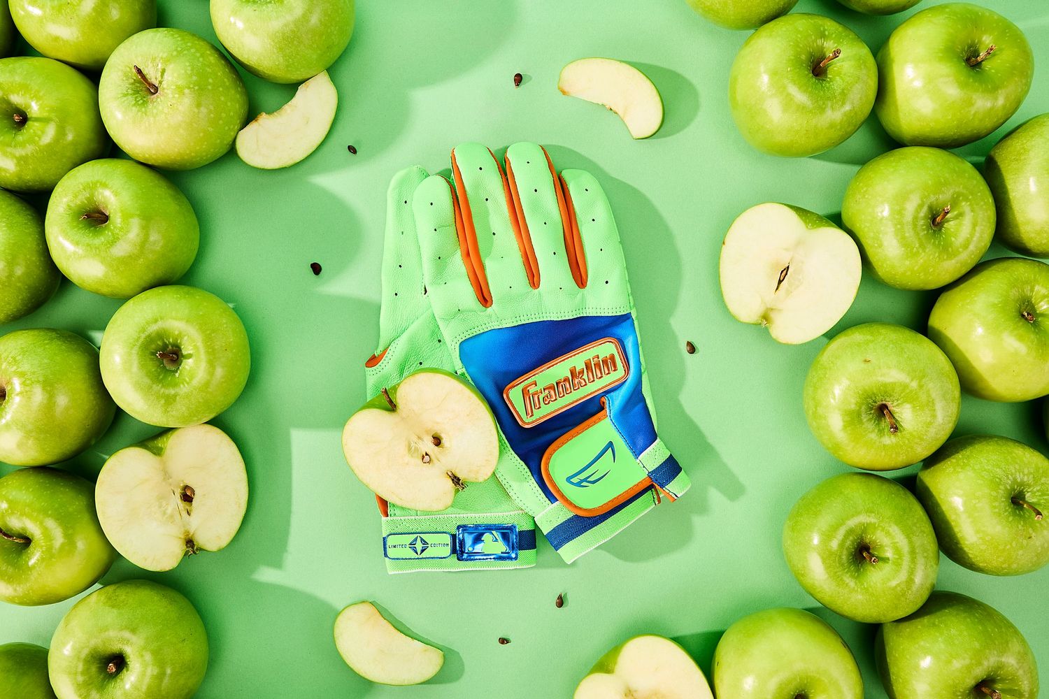 Fresh green Granny Smith apples and sliced apple pieces arranged on a mint green background with kitchen utensils.