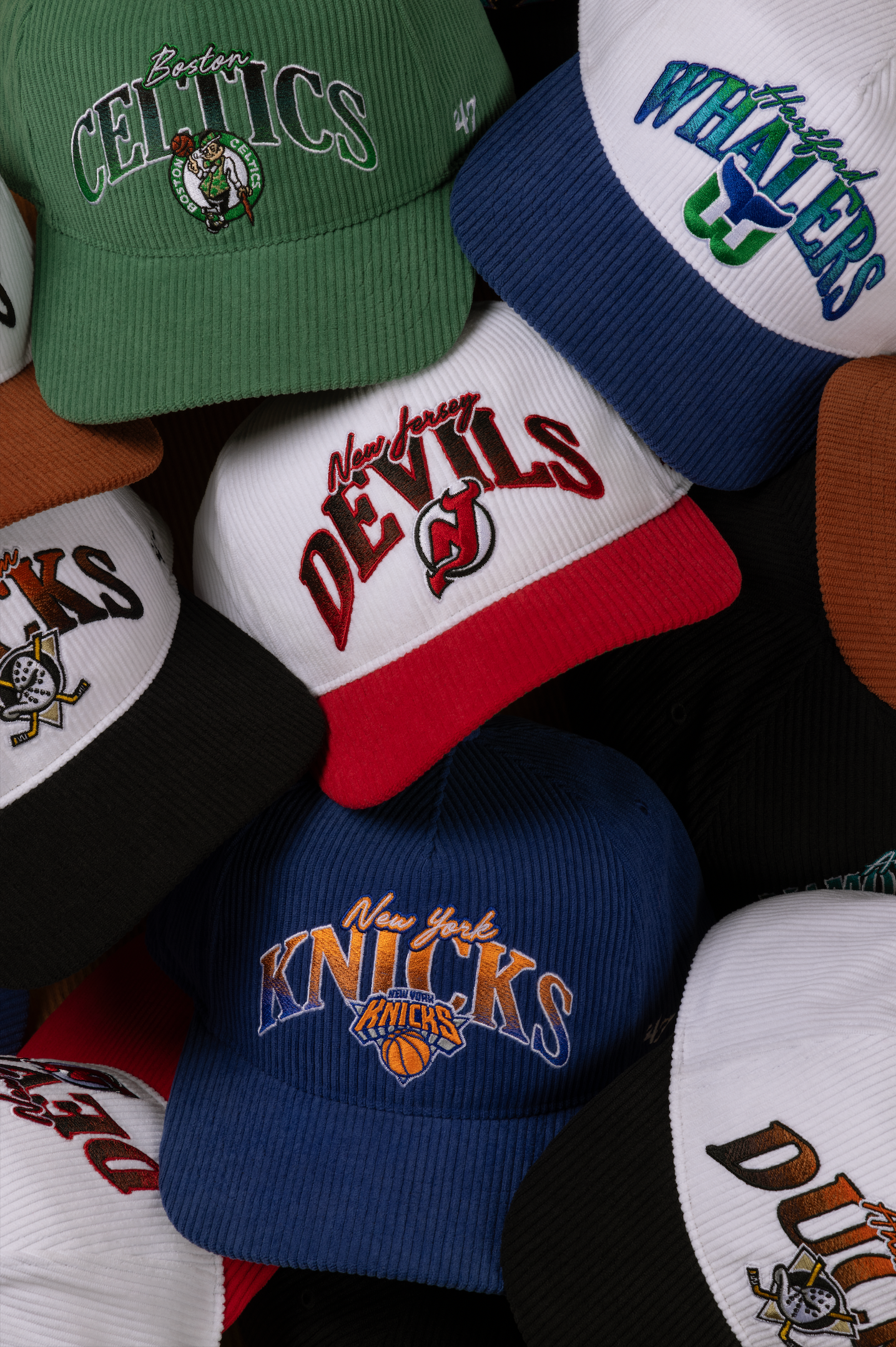 Collection of vintage NBA team baseball caps including Celtics, Knicks and other classic logos displayed together.