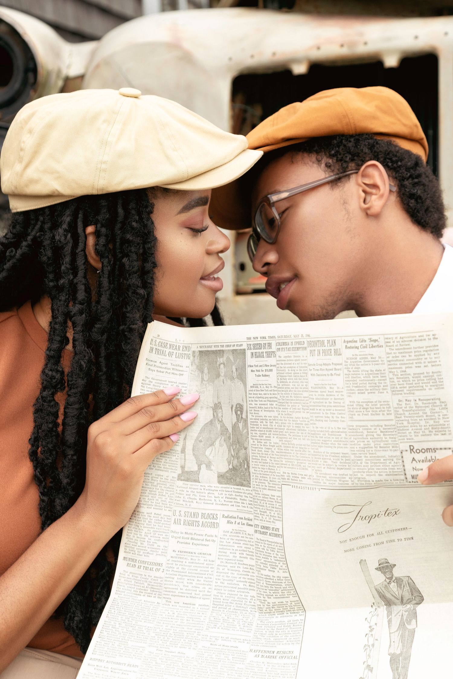 A romantic couple shares tender moments while playfully hiding behind a newspaper in a series of intimate photographs.