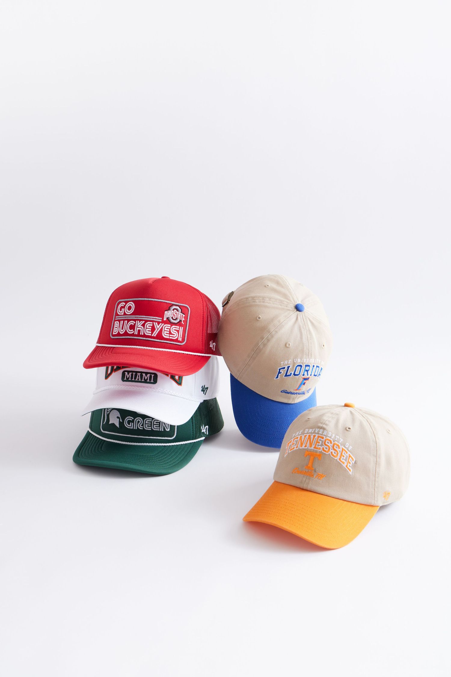 Collection of colorful baseball caps with embroidered logos displayed on white background including red, beige, green and blue styles.