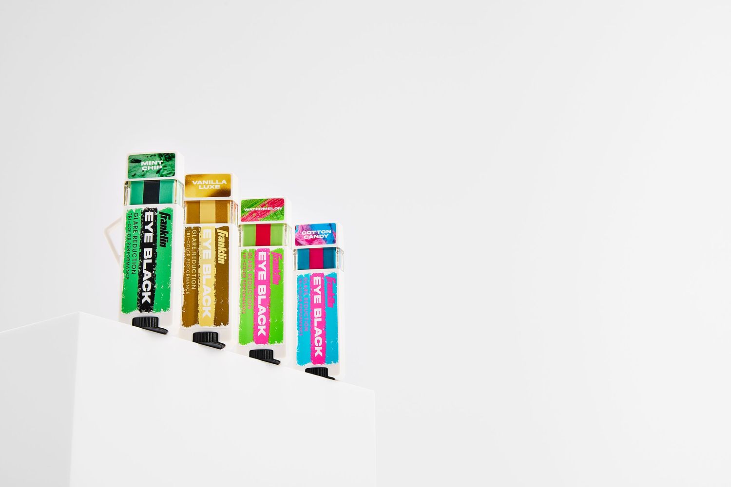 Colorful eyeblacks lined up against a white background, creating a minimalist display.