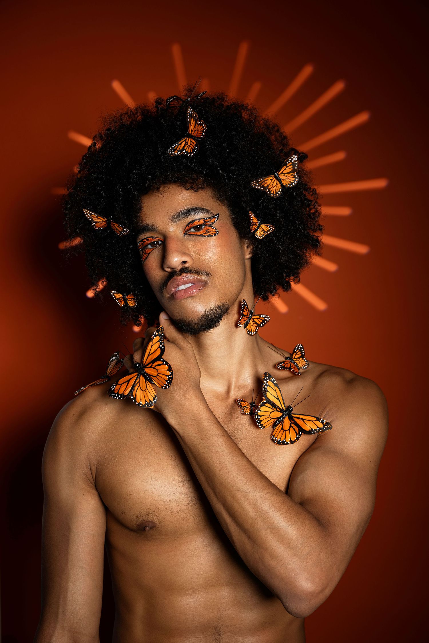 Artistic portrait series with orange monarch butterflies against a warm brown background with sunburst lighting effects.