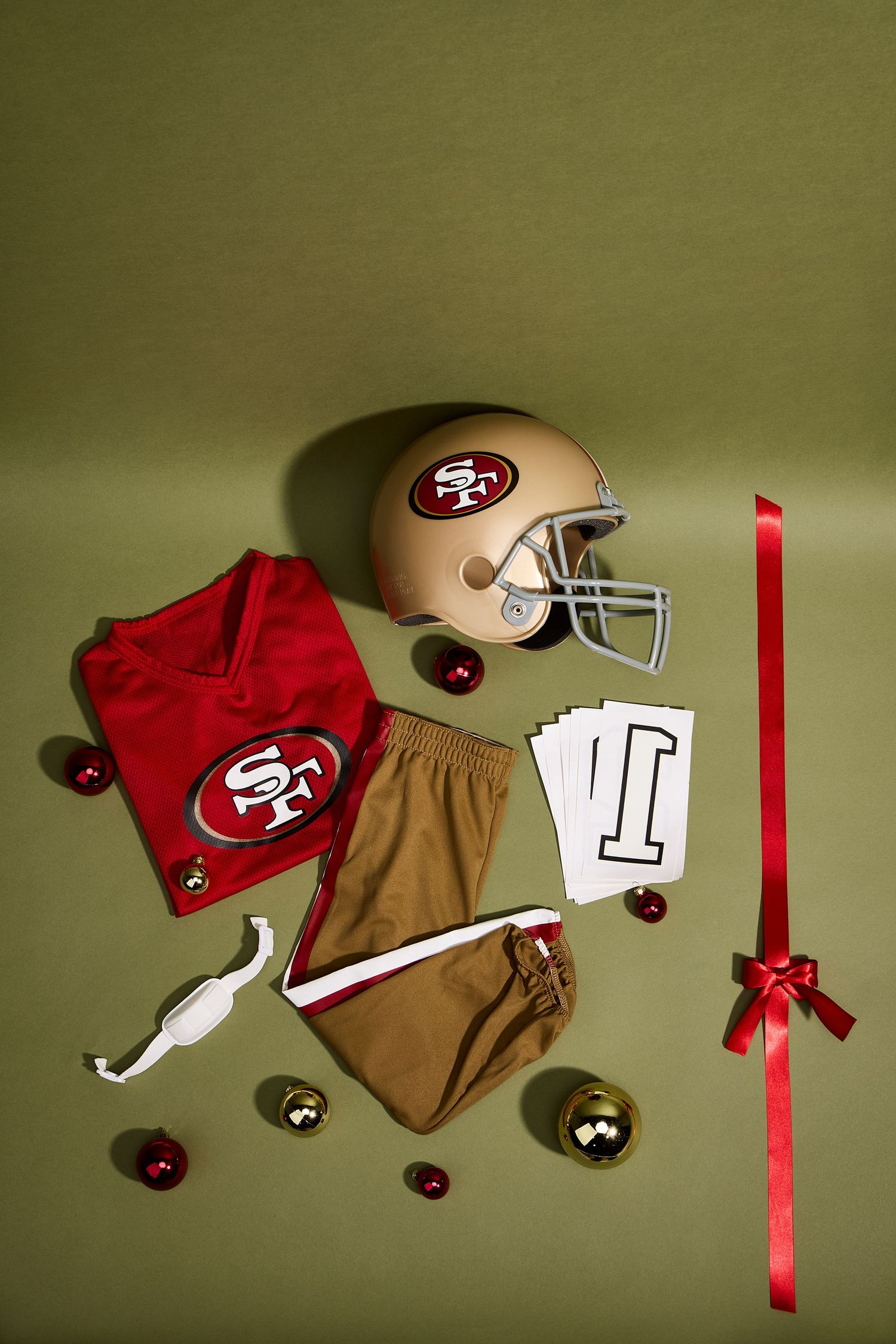 San Francisco 49ers football uniform and helmet arranged in a flatlay composition with red and gold elements.