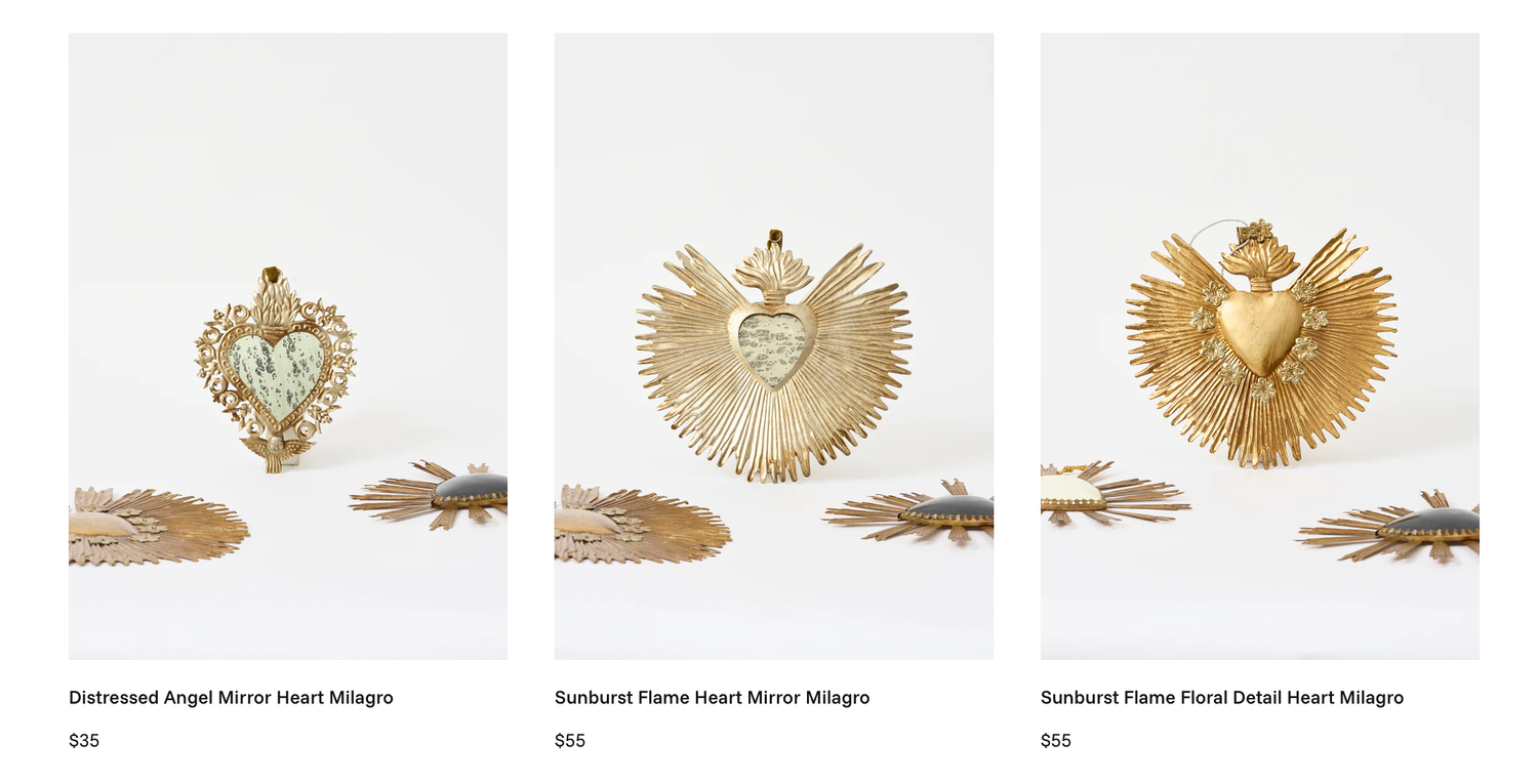 Three gold sacred heart milagro ornaments with angel and sunburst flame designs displayed on white background.