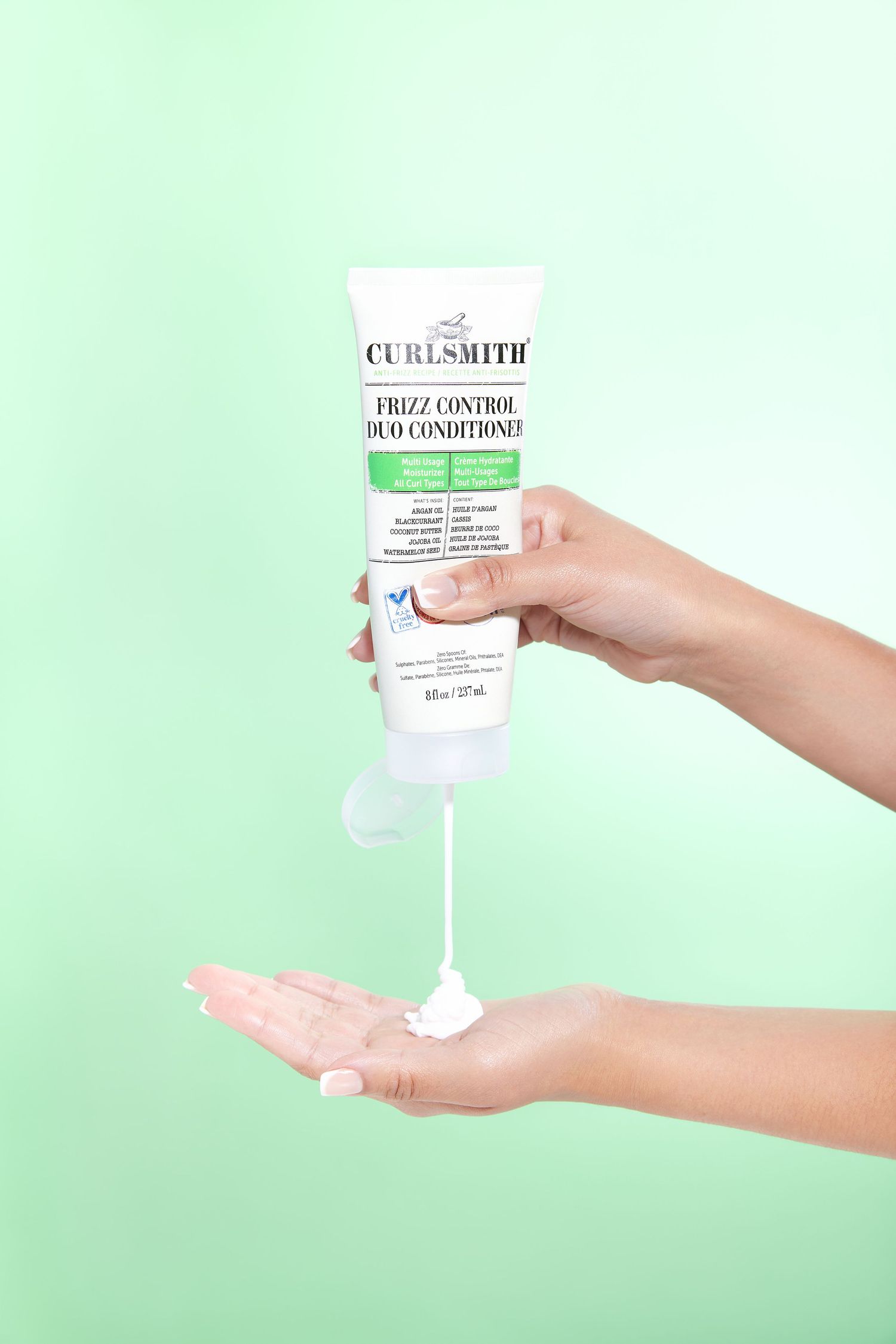 Four hands holding white hair care product bottles against a mint green background in a minimalist beauty product layout.