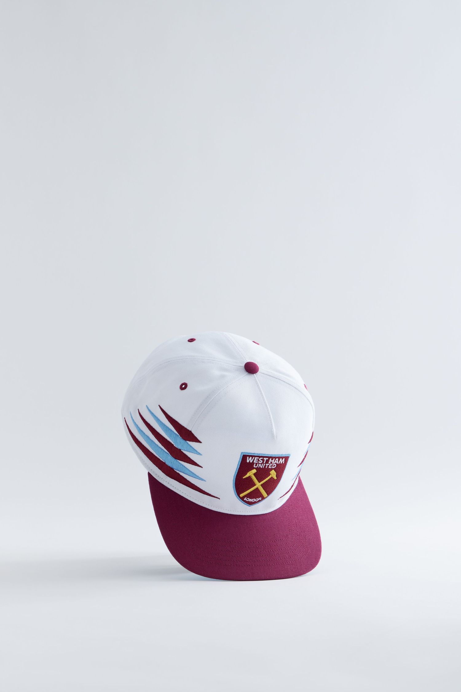 White and maroon baseball cap with geometric design shown from multiple angles on light gray background.