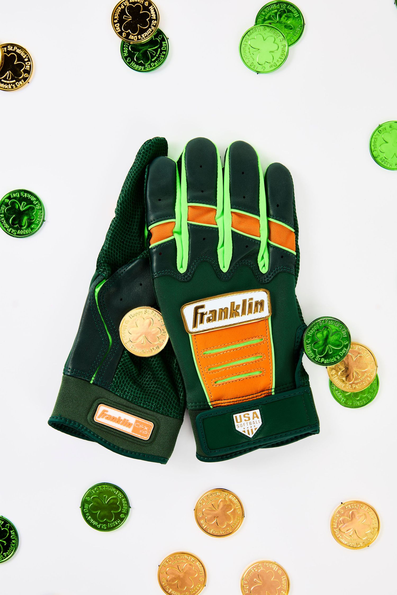 Black and green Franklin sports gloves with orange accents displayed on white background with scattered coins.