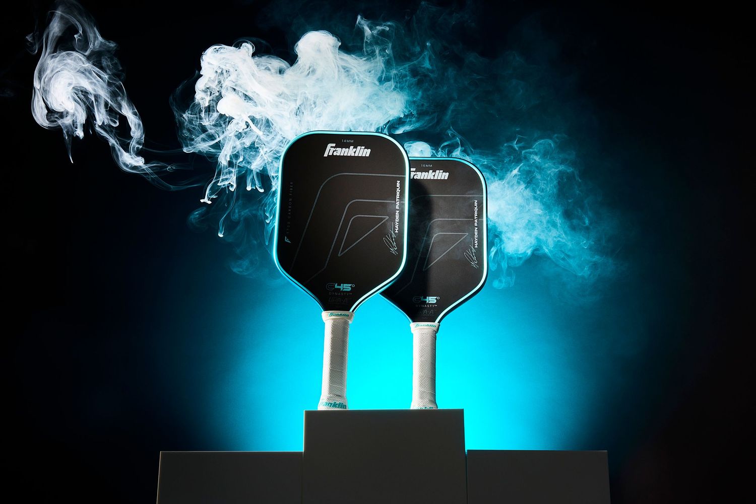Two car keys on a black pedestal with dramatic blue backlighting and swirling smoke effects.