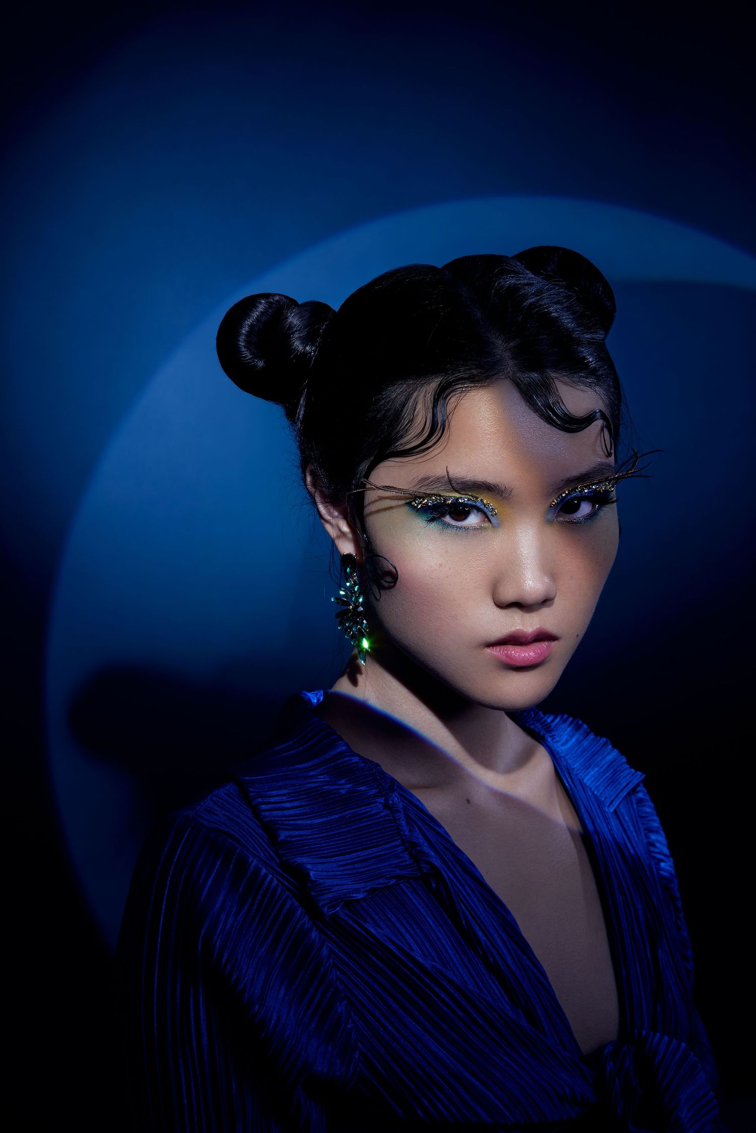 Dramatic portrait with blue lighting features vintage-inspired finger waves hairstyle and a royal blue velvet jacket.