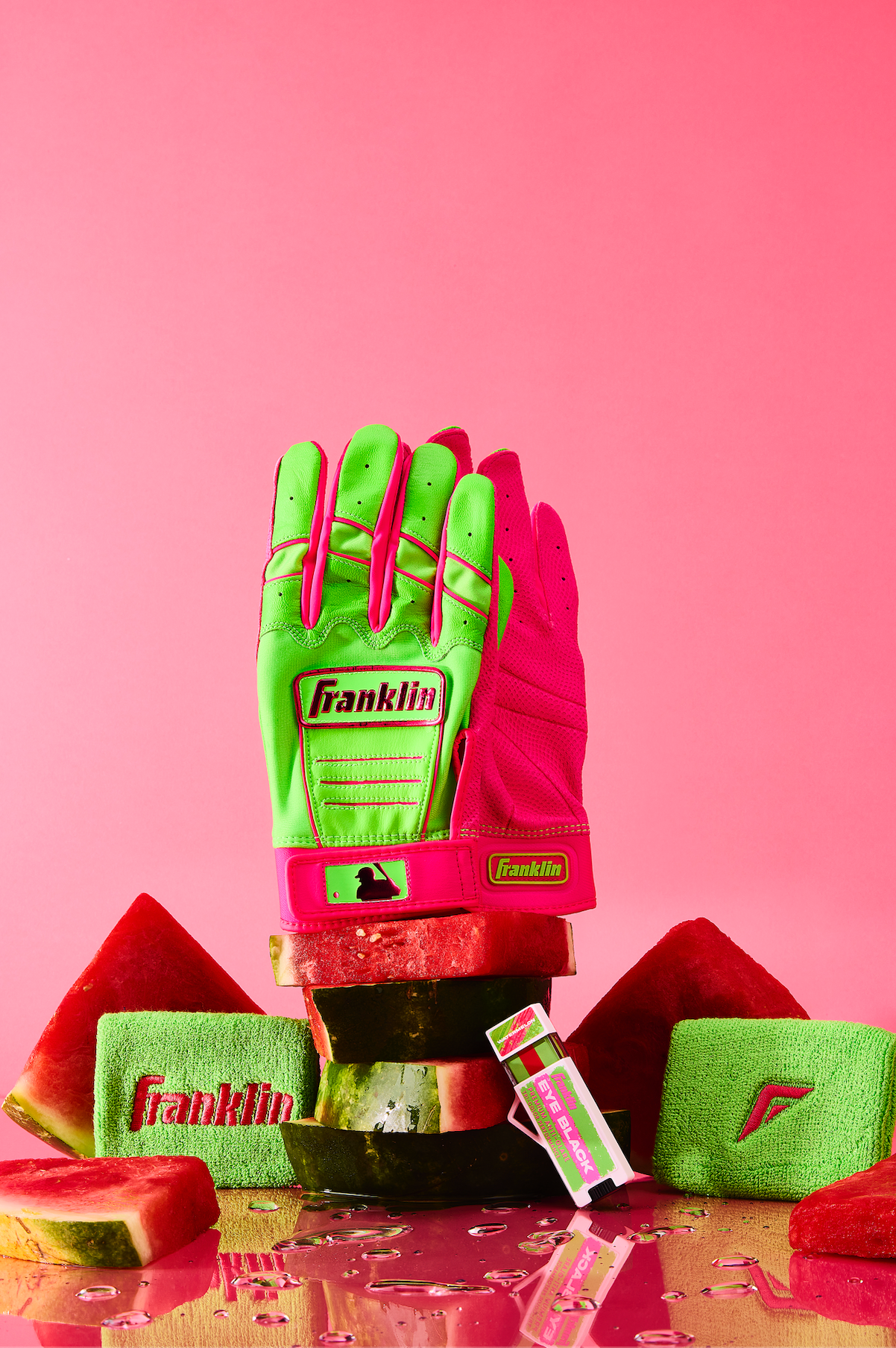 Franklin brand baseball gloves in neon green and pink colors arranged on a pink background with a creative lighting setup.