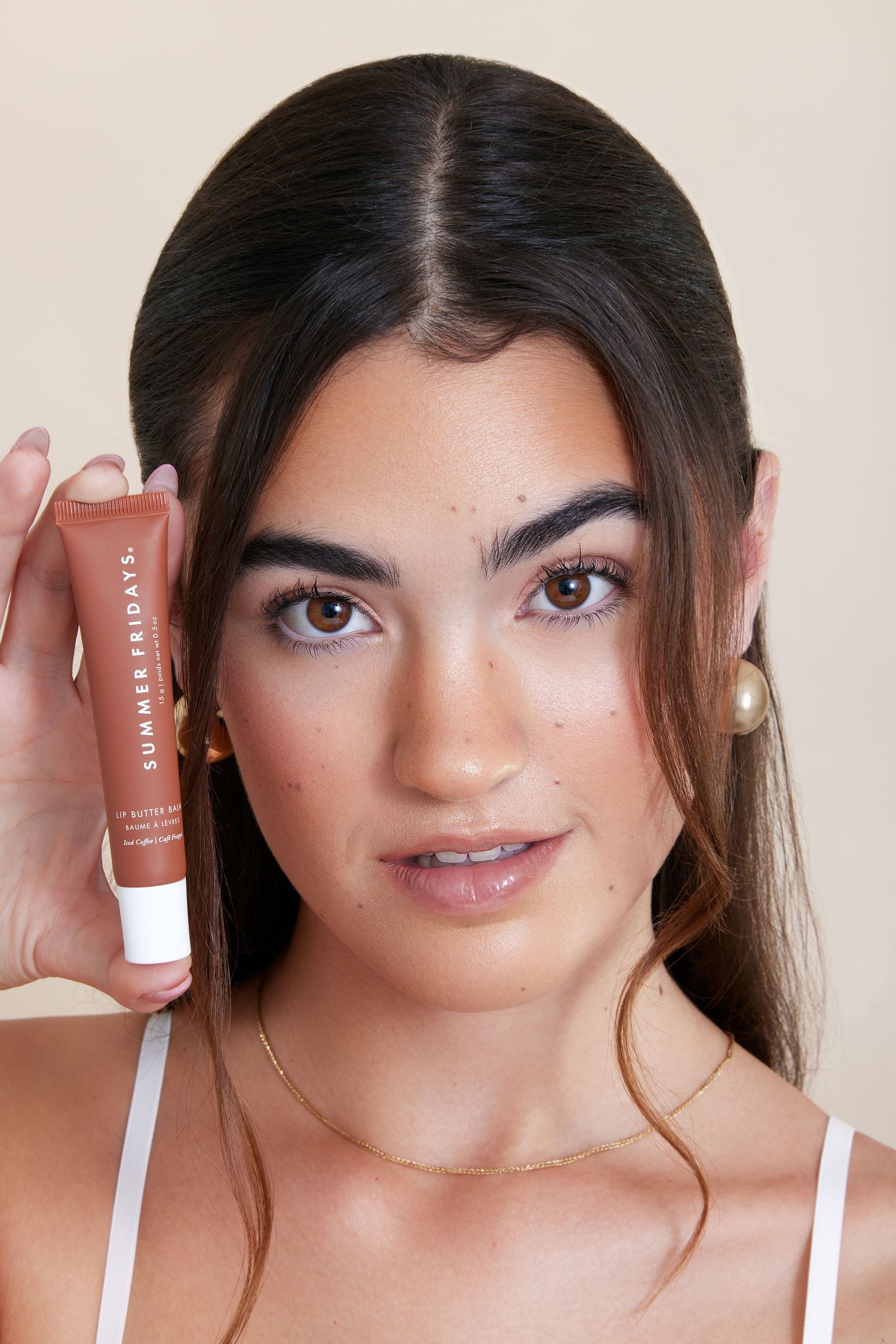 A series of four beauty shots showing lip gloss application and close-up makeup looks in warm neutral tones.