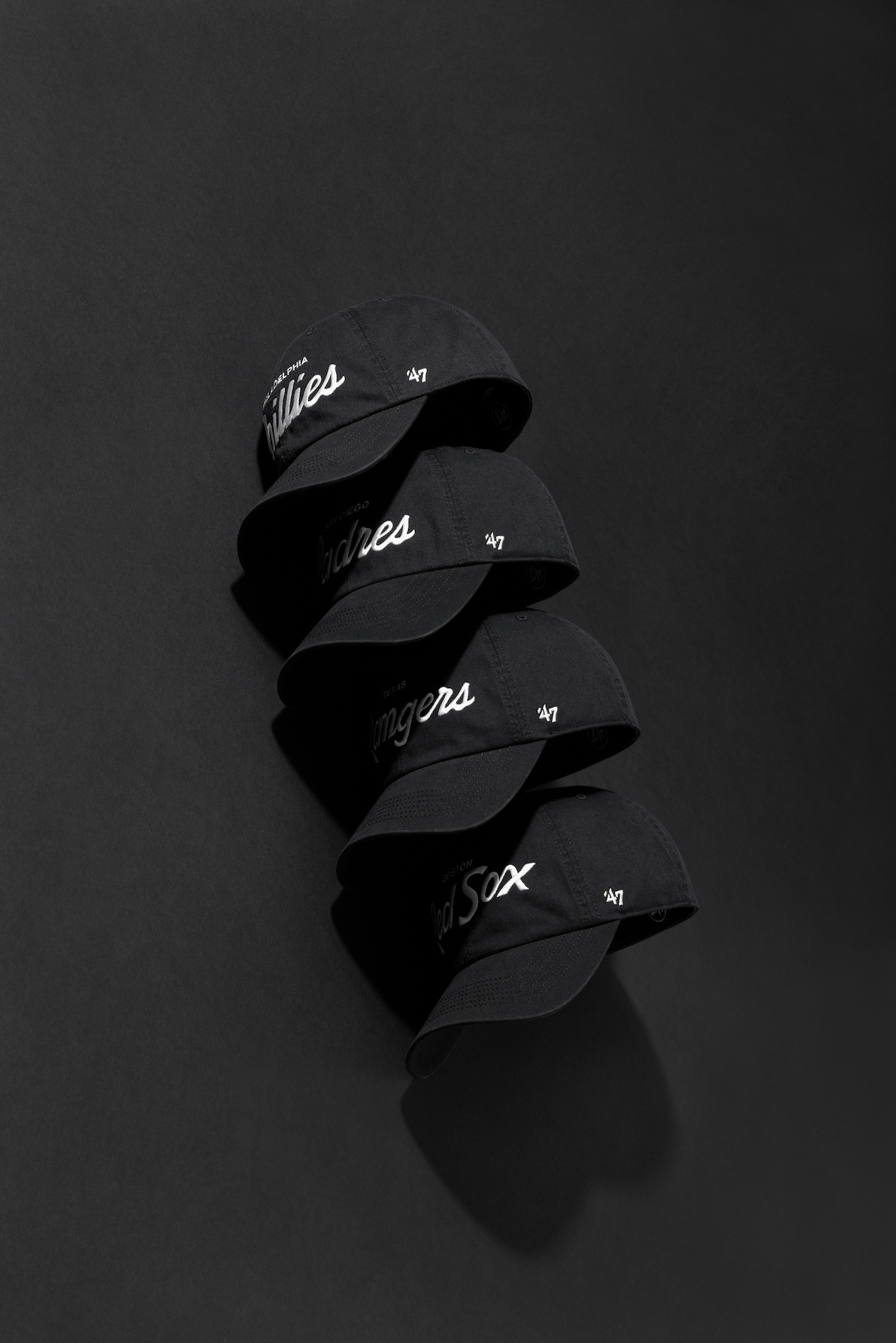 Black baseball caps with white logos arranged in a dynamic shadow pattern against a dark background.