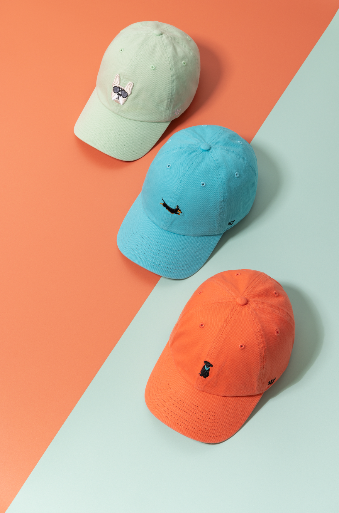Minimalist baseball caps in pastel mint, turquoise, and coral orange colors arranged on peach background.