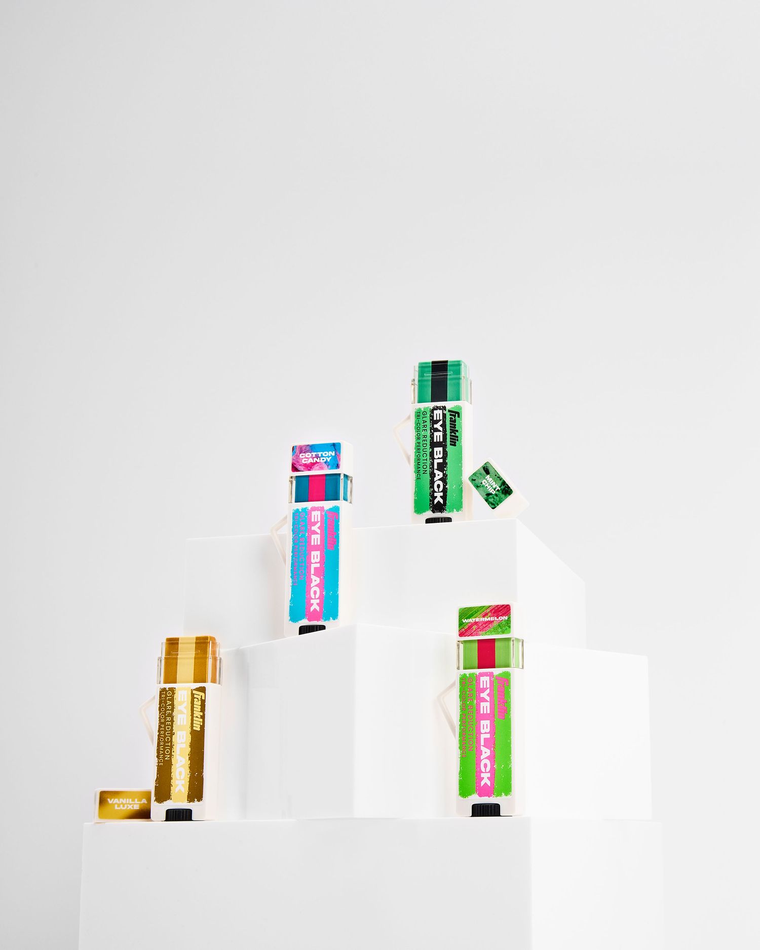 Colorful eyeblack tubes arranged in a minimalist composition on white background.