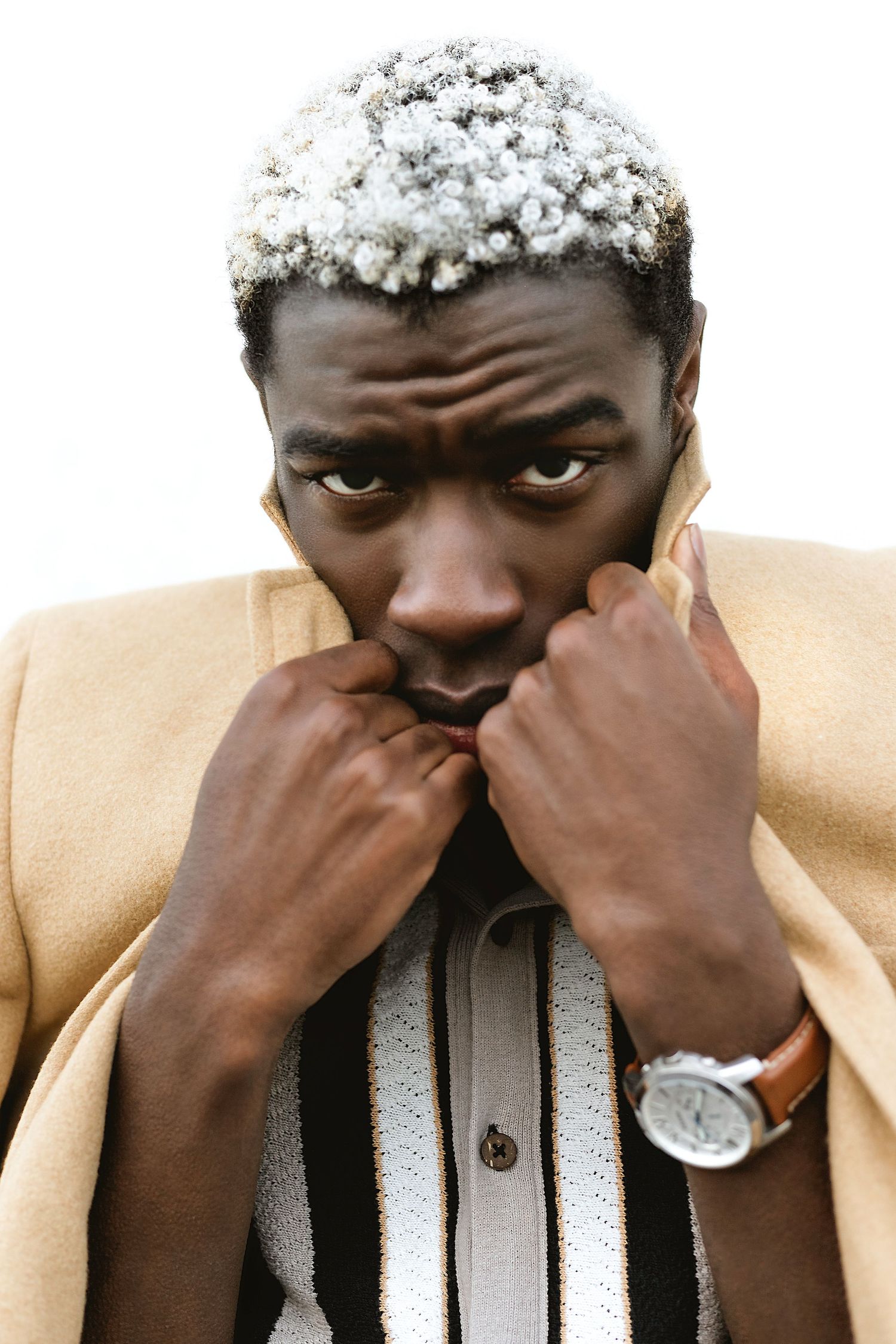 Three identical images show a person in a beige jacket pinching their nose while looking at the camera.