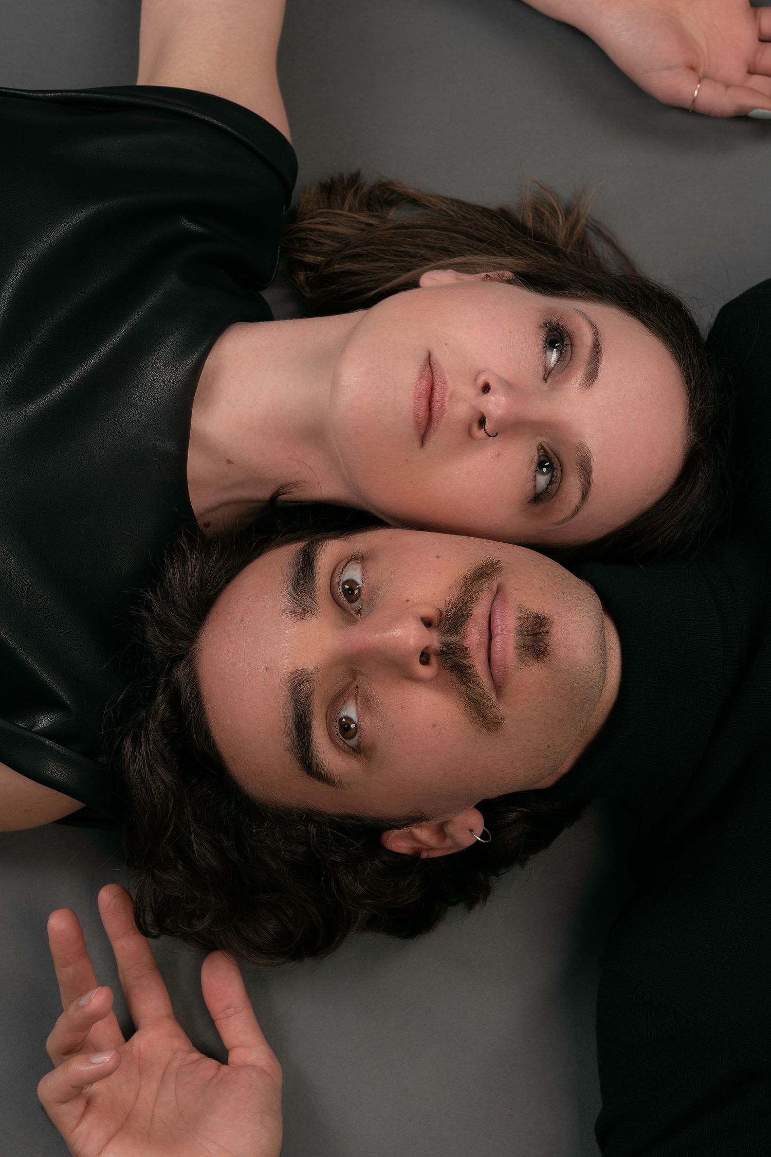 A series of black and white artistic portraits showing a person lying down against a dark background.