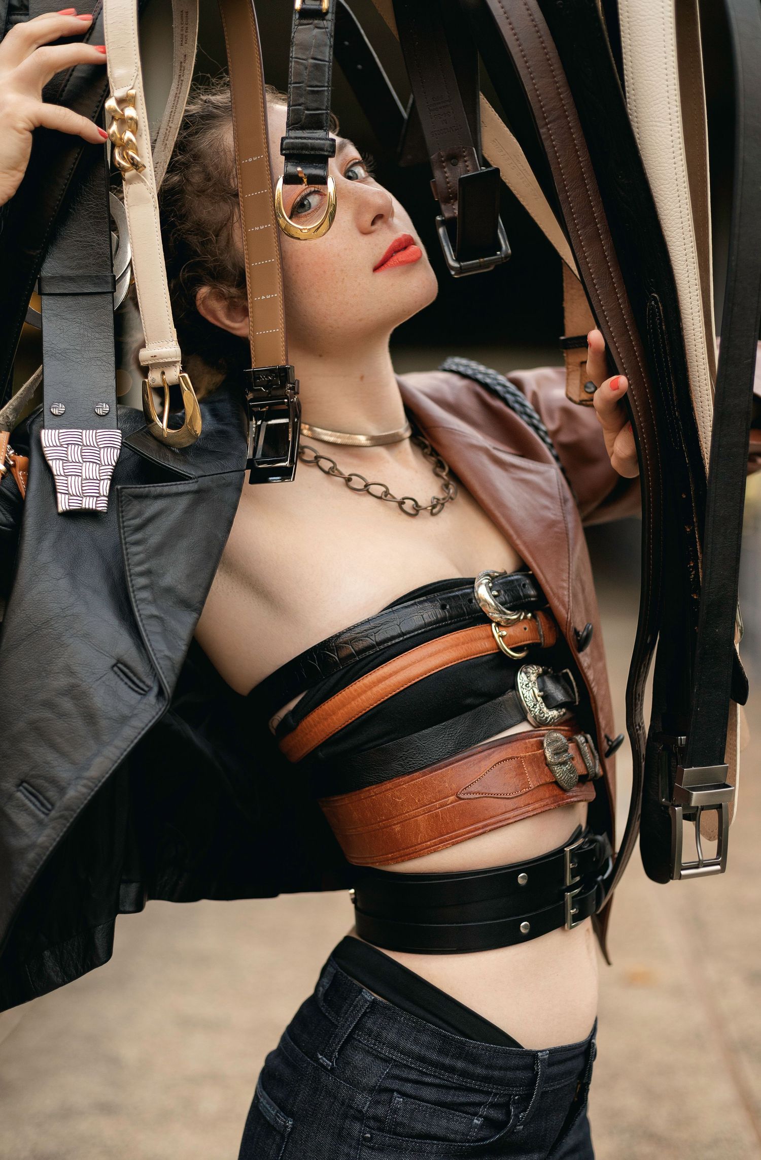 Leather harness and belt accessories displayed on a model against a neutral background.
