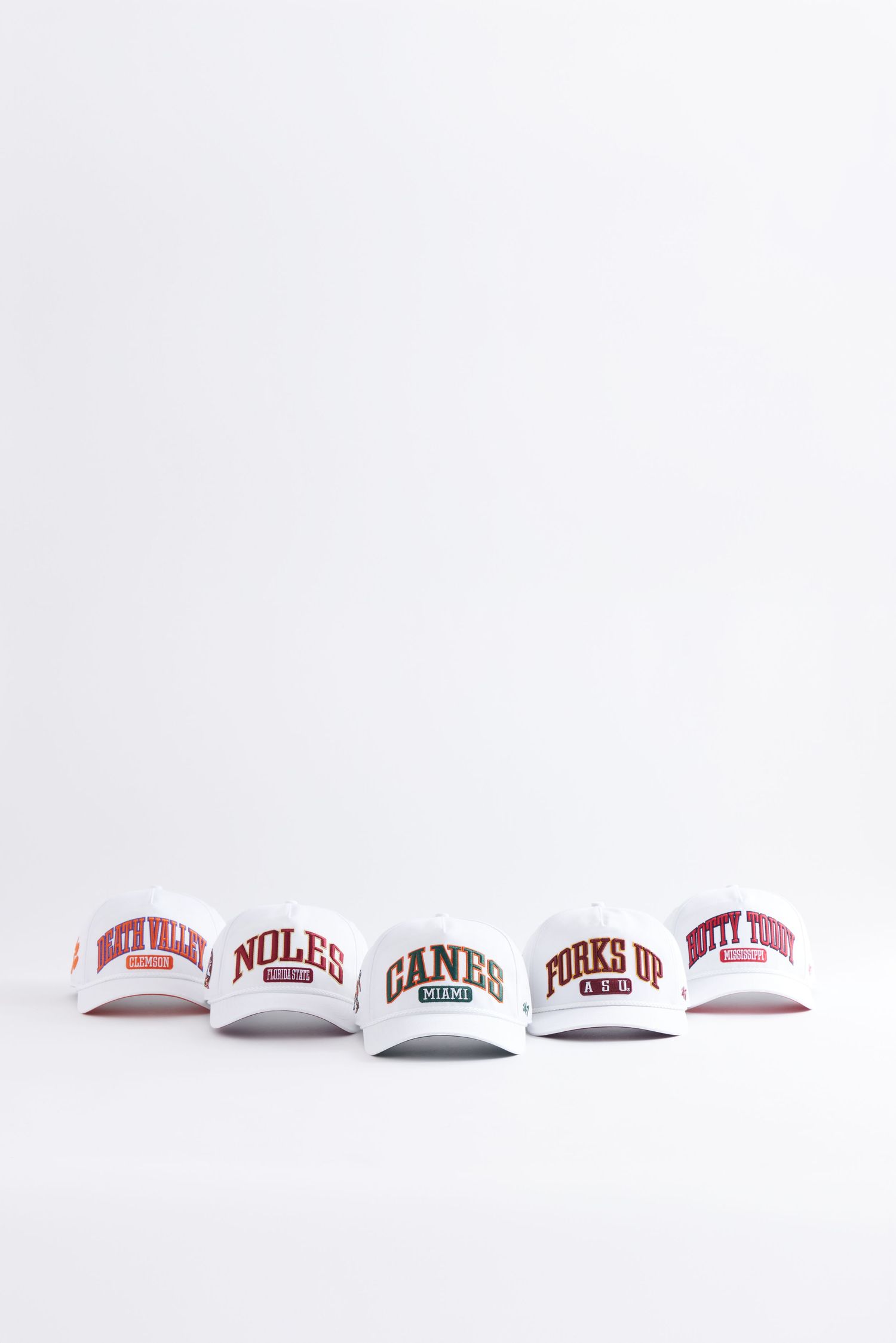 A row of curved-brim baseball caps with university and sports team logos displayed on a white background.