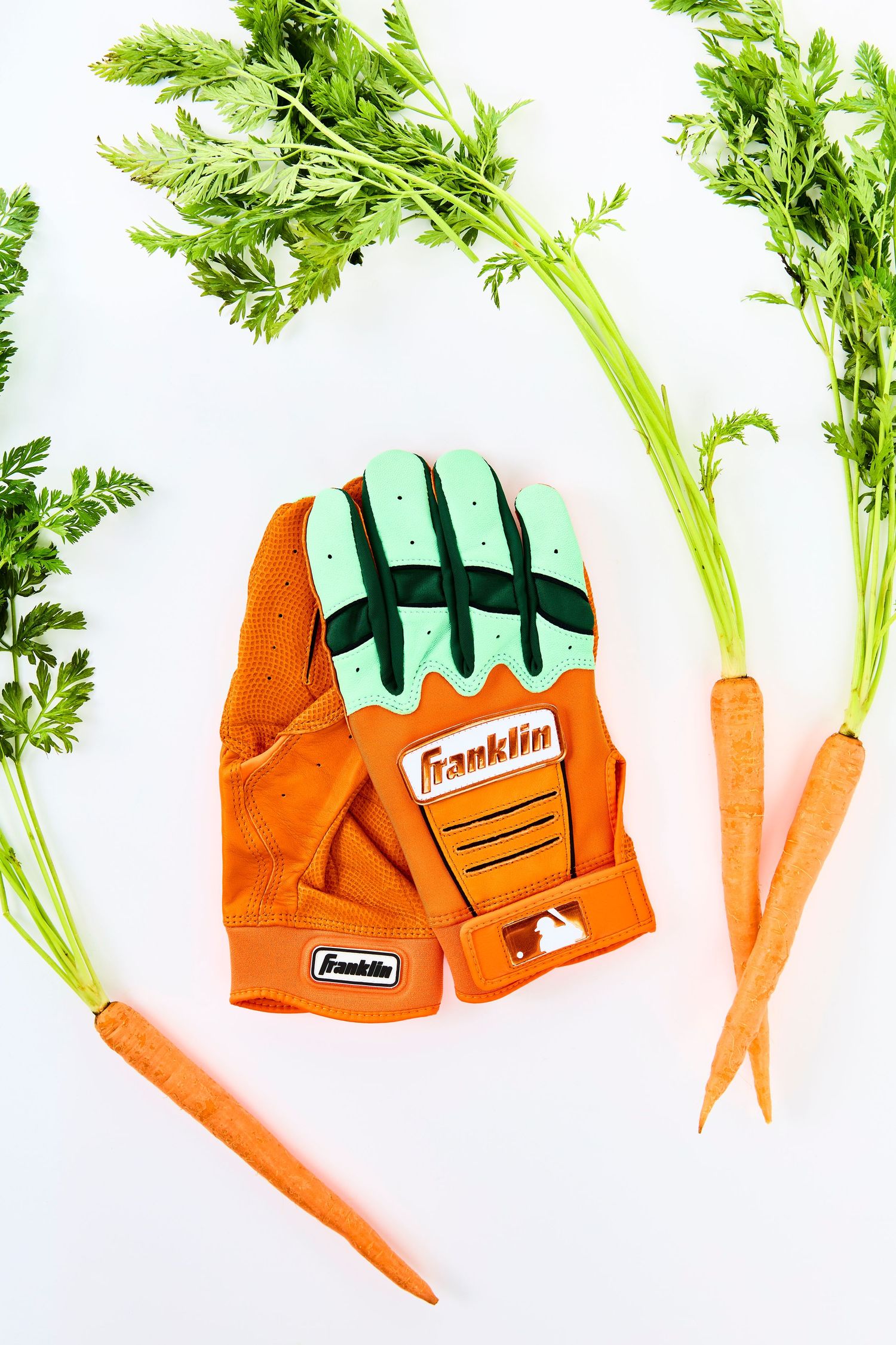 Fresh orange carrots with green leafy tops arranged in a creative sequence with gardening gloves.