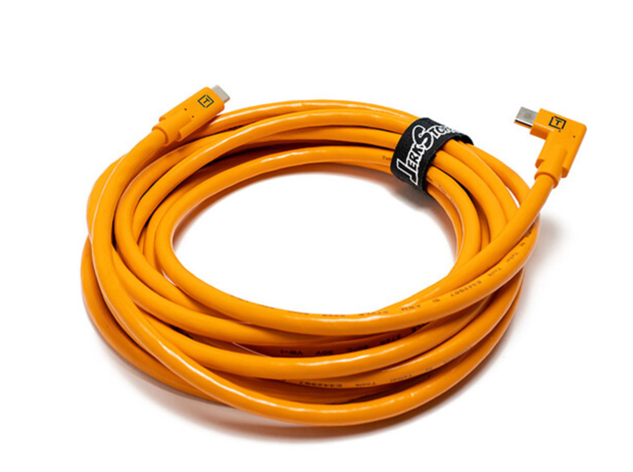 Bright orange coiled USB cable with right-angle connector and velcro tie, ideal for tethered photography sessions.