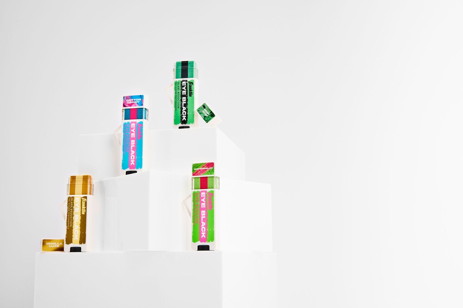 Colorful assortment of battery cells arranged in a row showing different sizes and brands against white background.