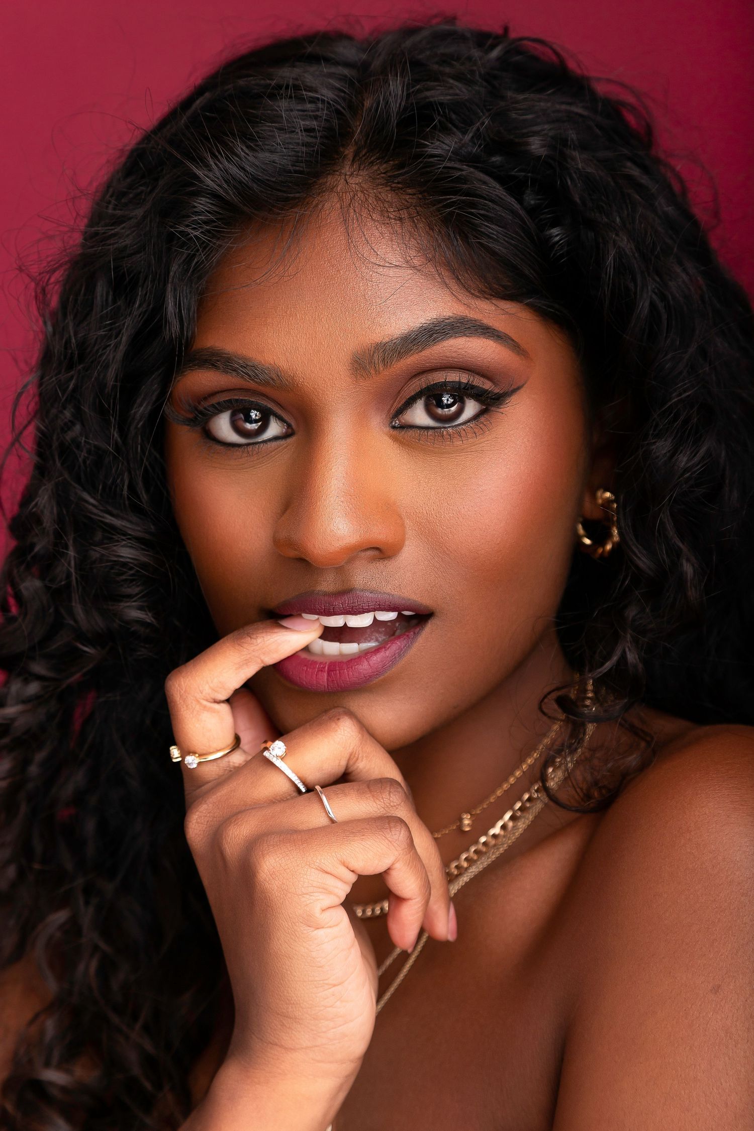Portrait series showing glamorous makeup with pink lipstick and gold jewelry against a deep red background.