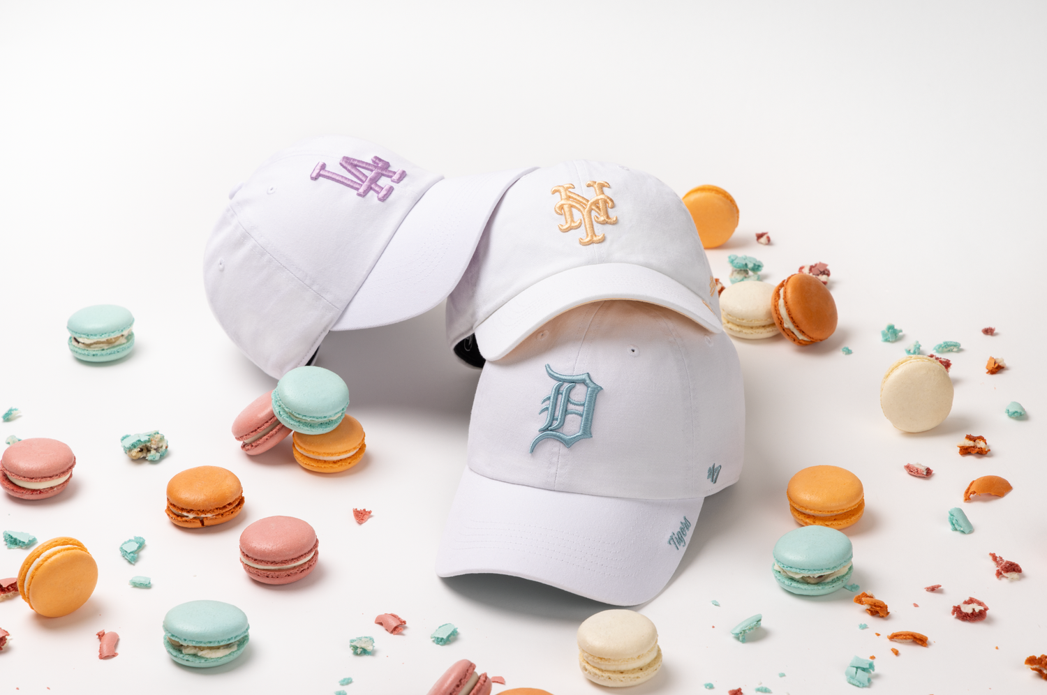 Colorful French macarons scattered around white paper and packaging materials on a light background.