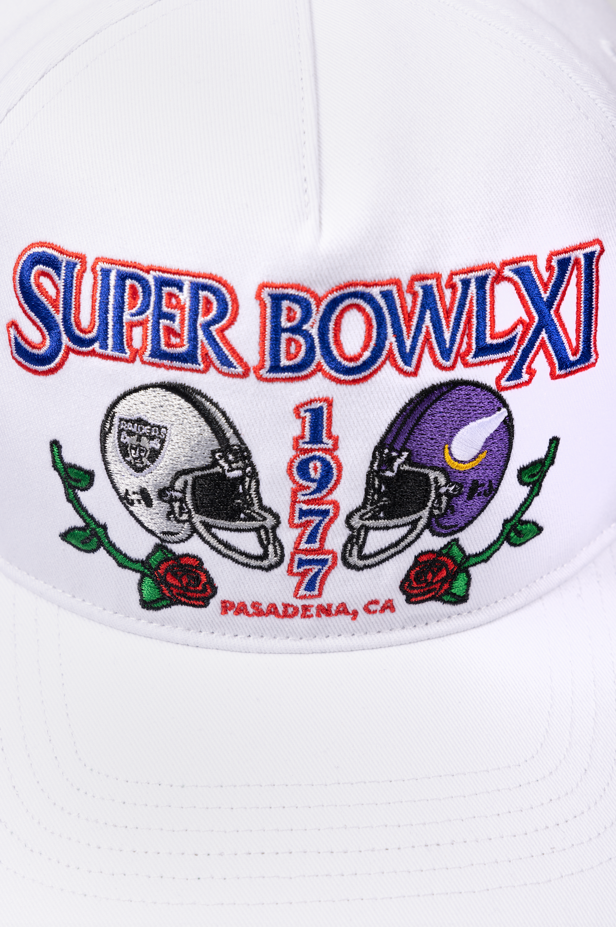 Vintage Super Bowl XI white baseball cap with embroidered team helmets and Pasadena CA text in red and blue colors.