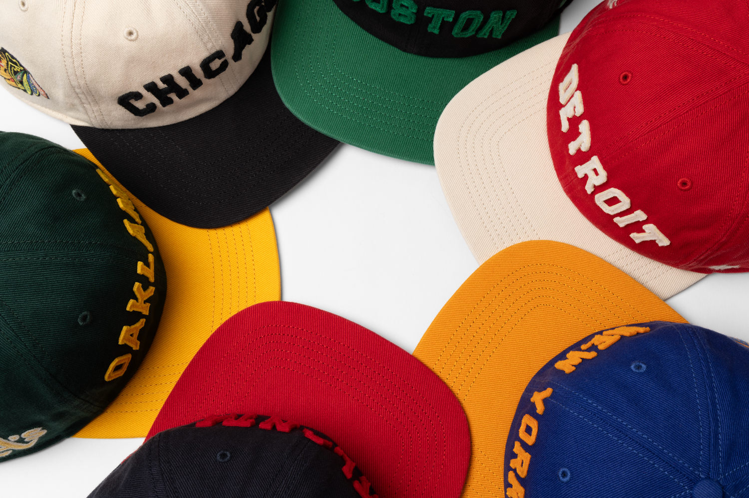 A collection of colorful baseball caps including red, blue, green, yellow and white arranged on a white background.