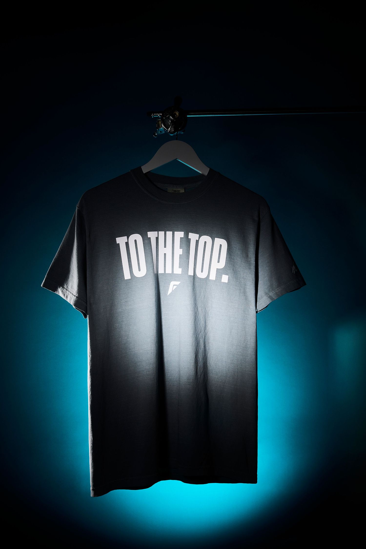 Black t-shirt with white text photographed against blue backlit background in multiple angles.