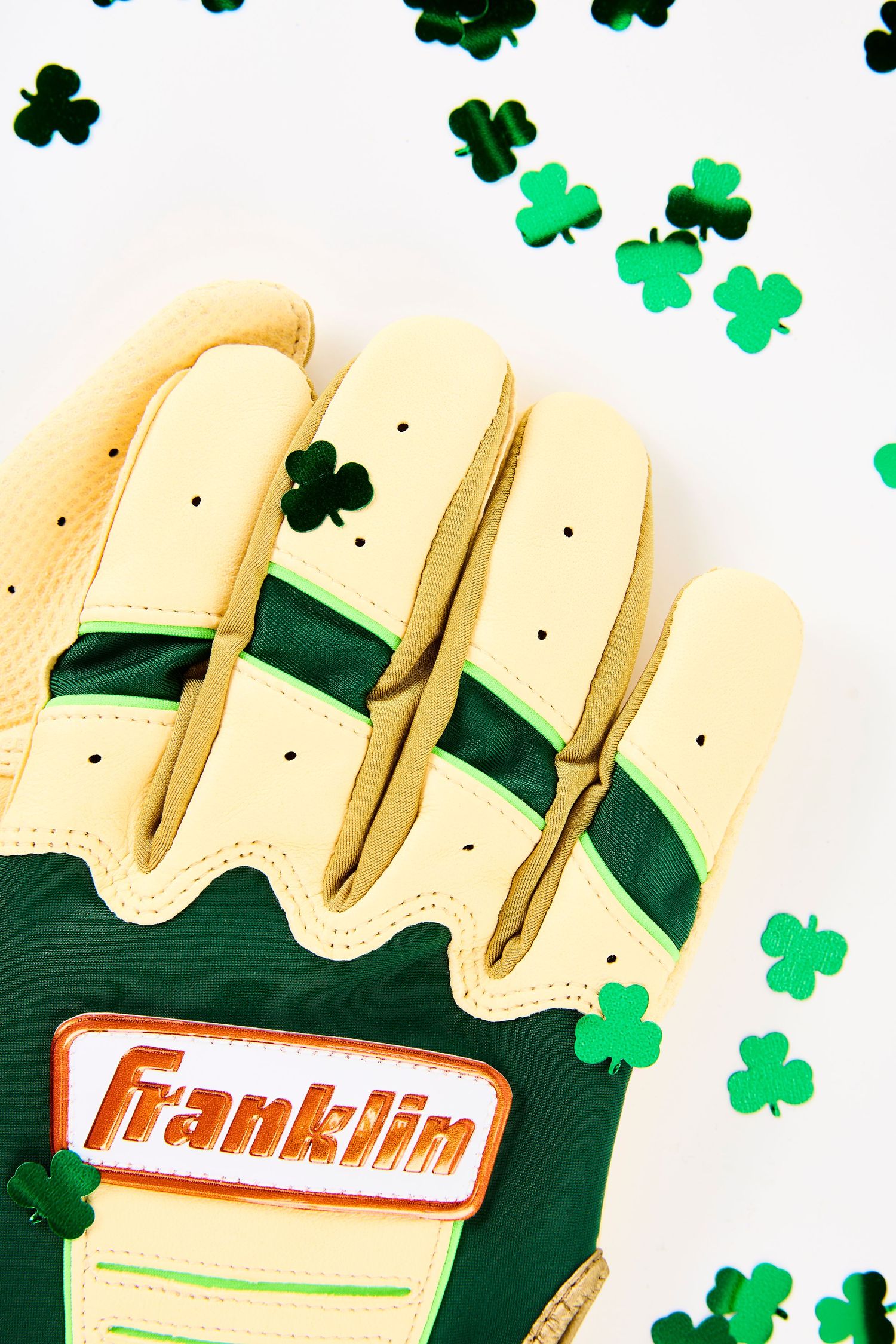 Green and cream Franklin baseball glove surrounded by floating shamrock decorations on white background.