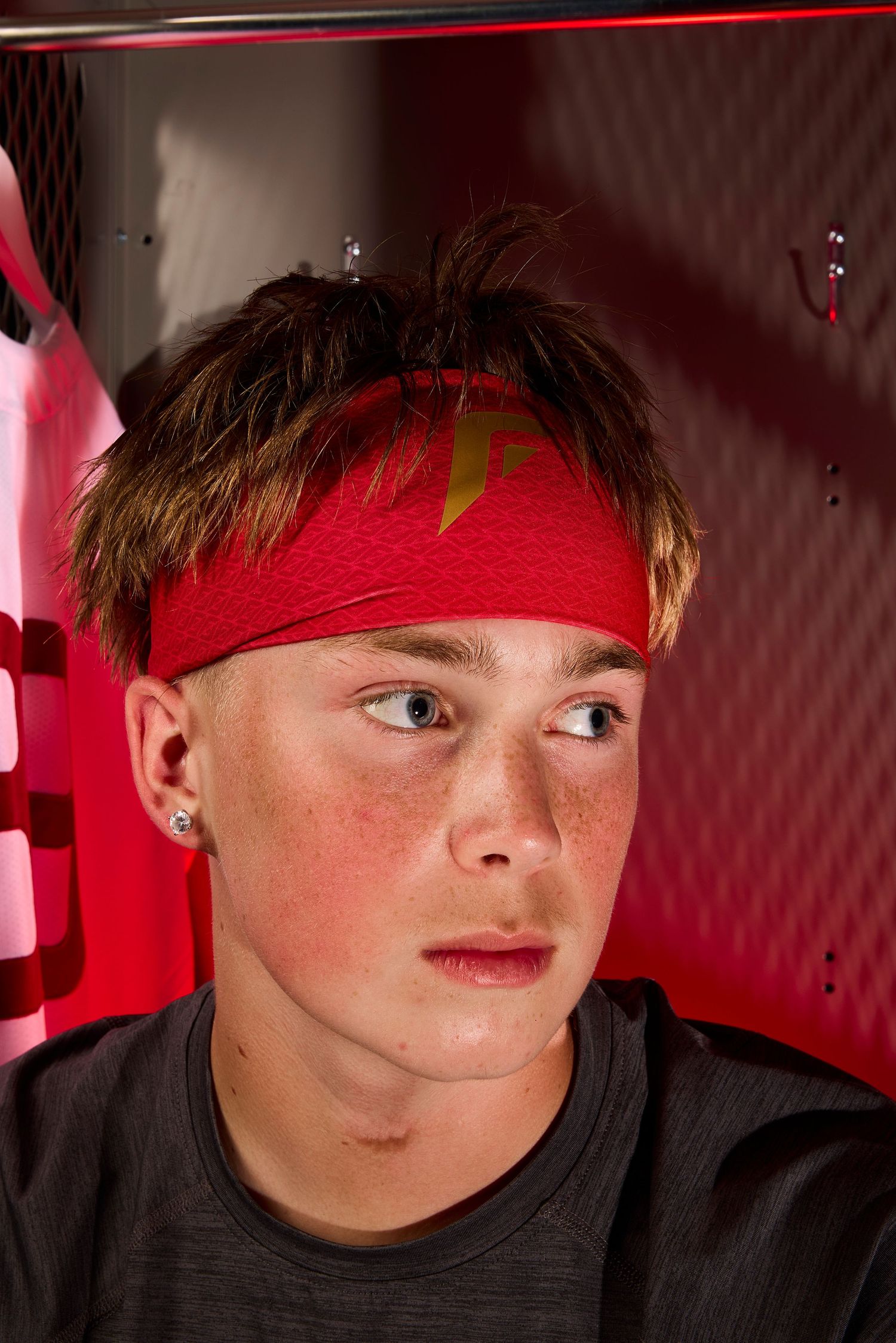 A person wearing a red headband with a yellow symbol sits in a dimly lit red space.