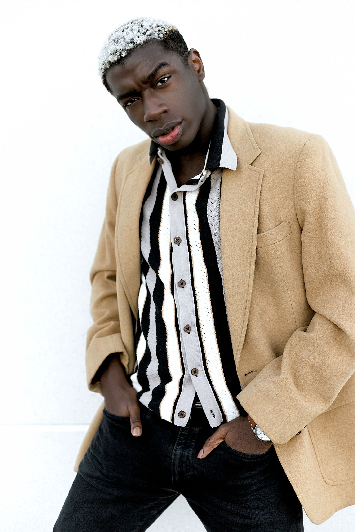 Fashion model in beige blazer and striped shirt poses in multiple dynamic angles against white background.