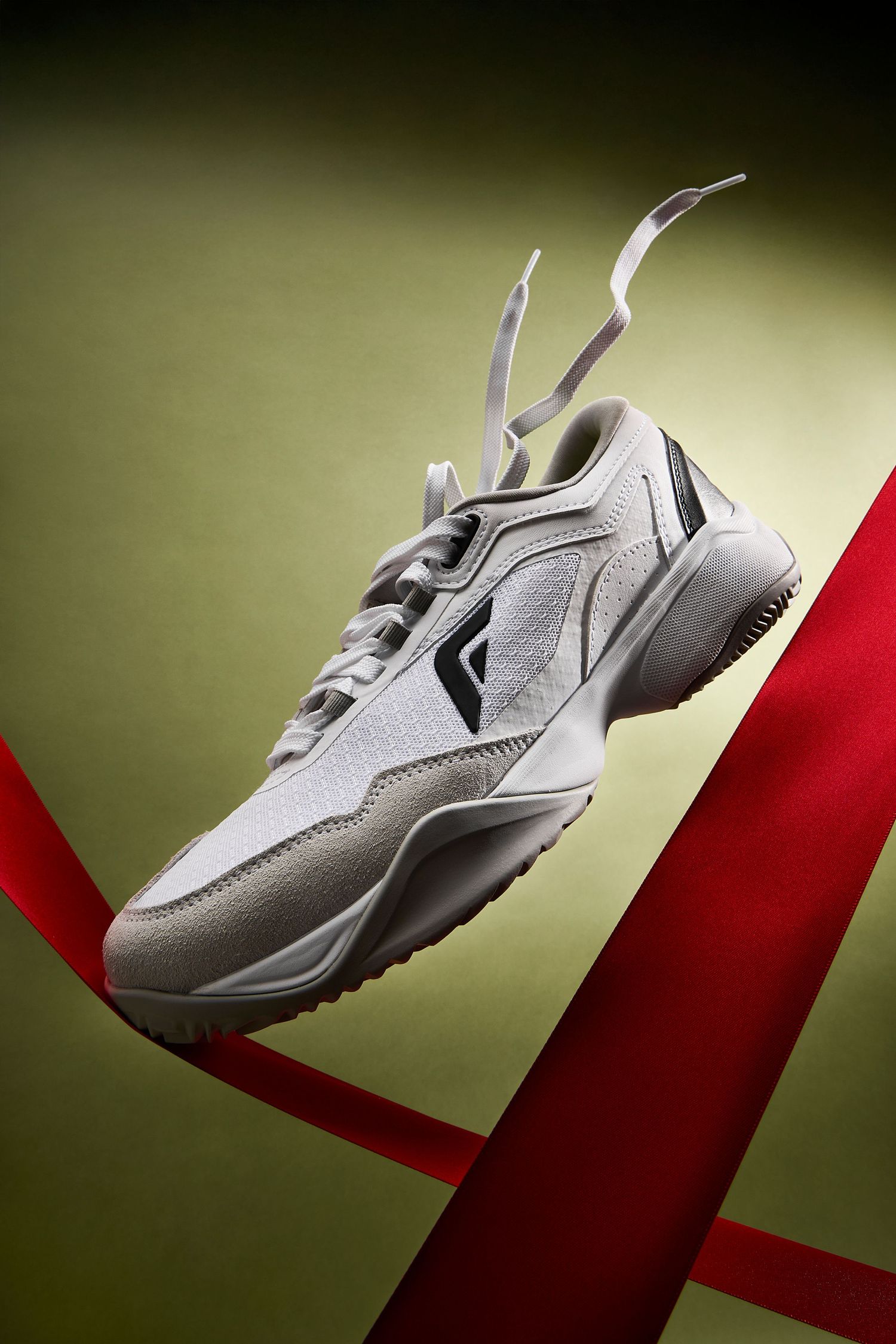 White athletic sneaker floating and rotating against a dark background with red diagonal element.