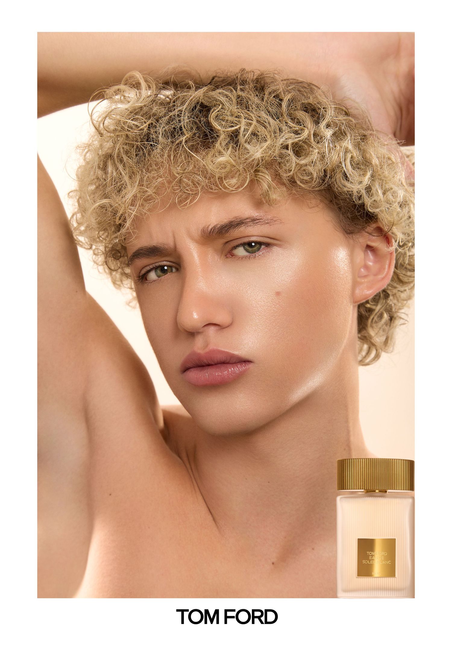 Tom Ford fragrance ad featuring a young model with blonde curly hair posing elegantly against a neutral background.