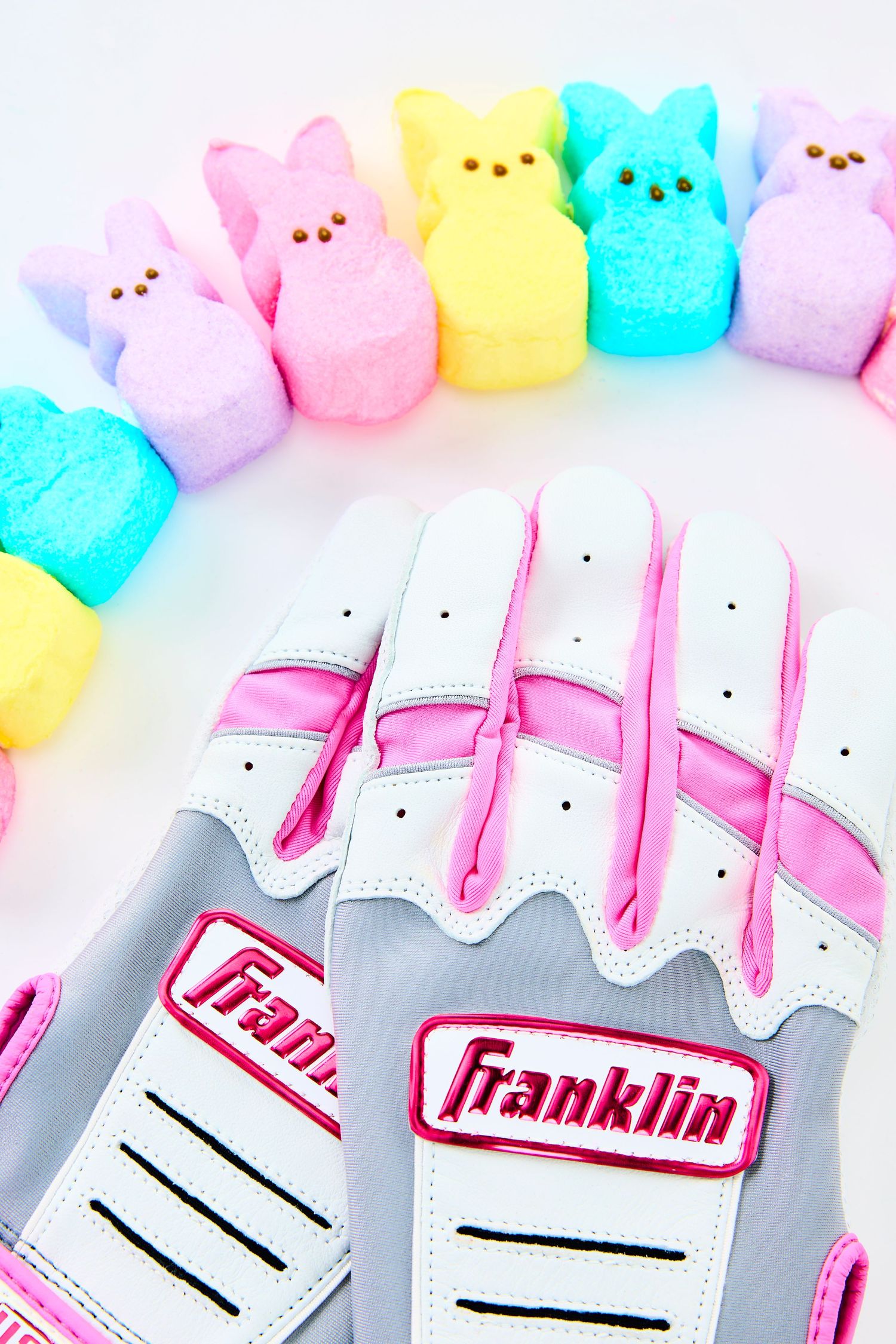 White Franklin baseball gloves arranged in a row with colorful Easter Peeps candy decorating the top border.