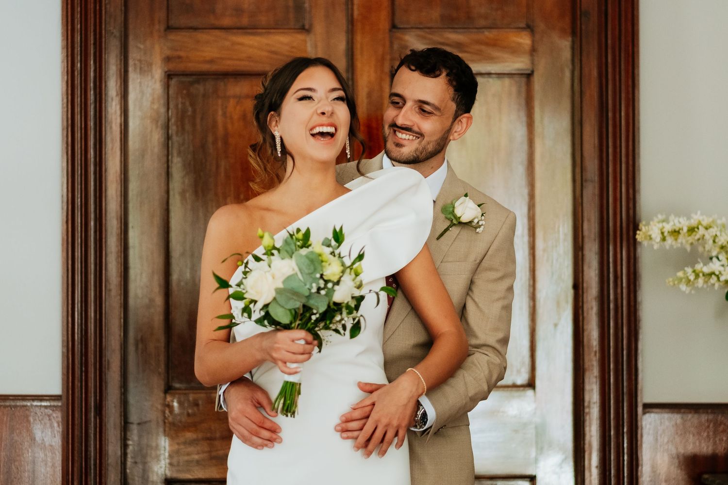 Romantic wedding couple embracing in an elegant room with wooden doors and natural light. Wedding in Gibraltar