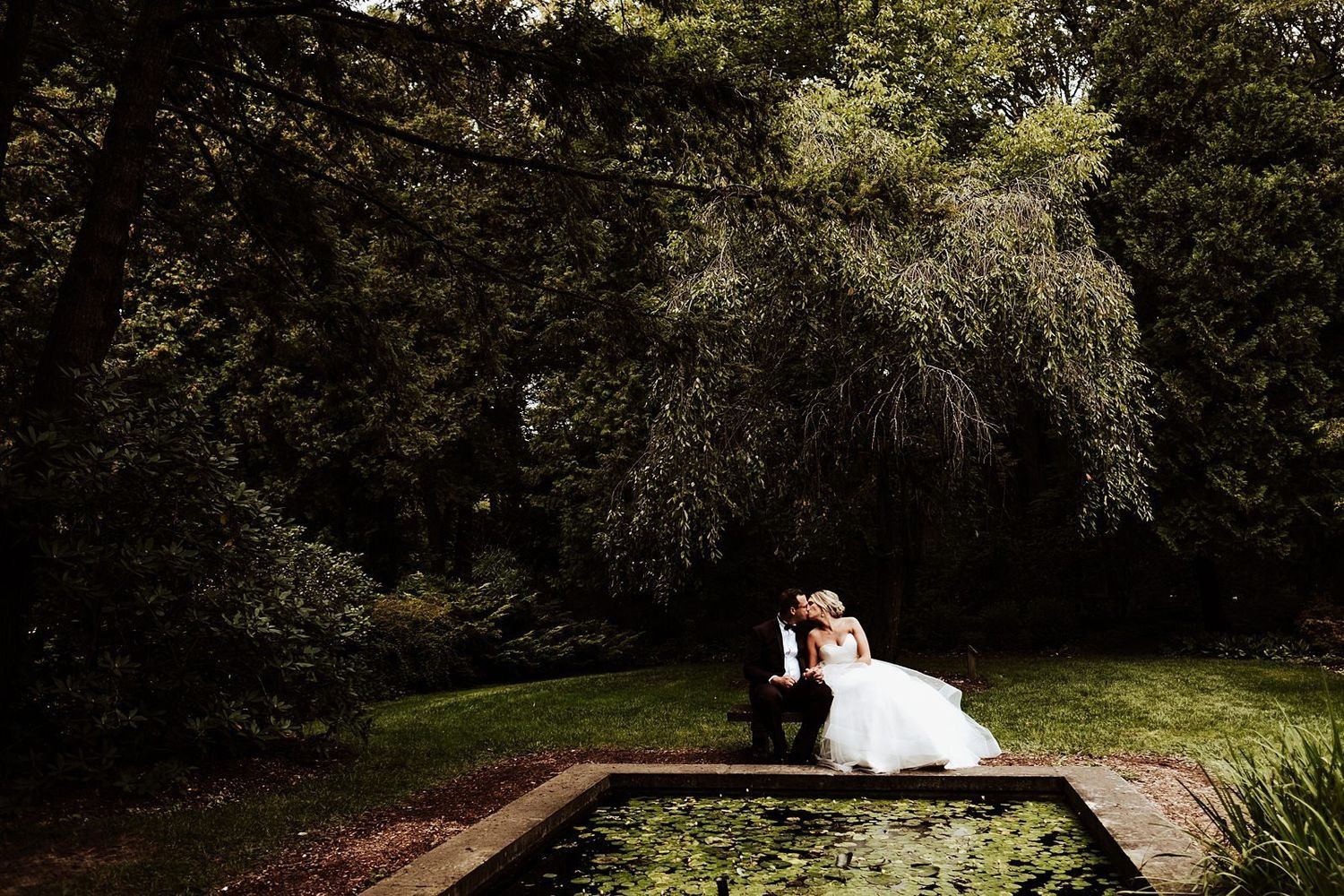 Shannon and Karel sharing a quiet moment on a garden bench with a beautiful pond view in Grand Rapids.