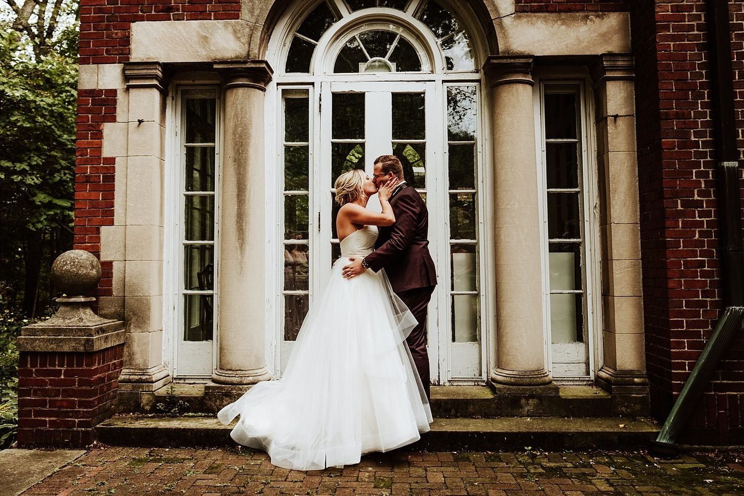 Newlyweds Shannon and Karel sharing a romantic kiss in front of a historic Grand Rapids facade