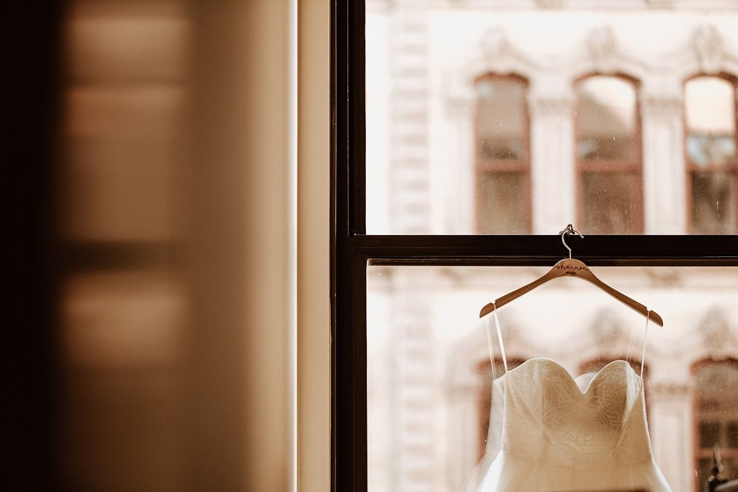 Shannon’s wedding dress hanging against the Grand Rapids skyline windows