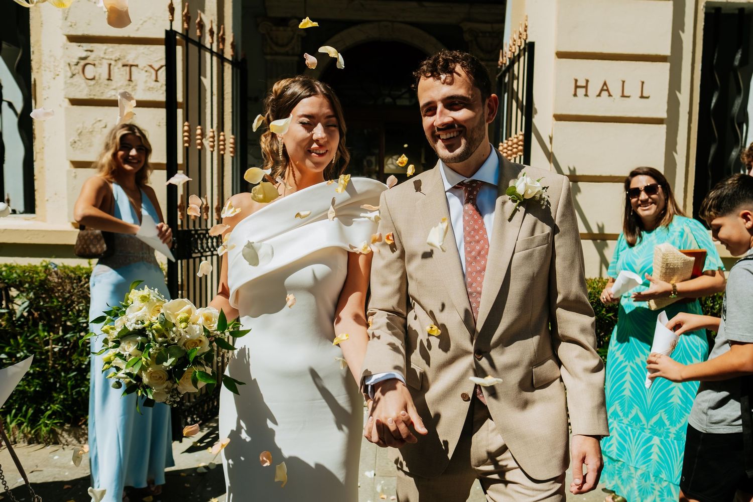Wedding party and guests gathered outside a historic stone building entrance.