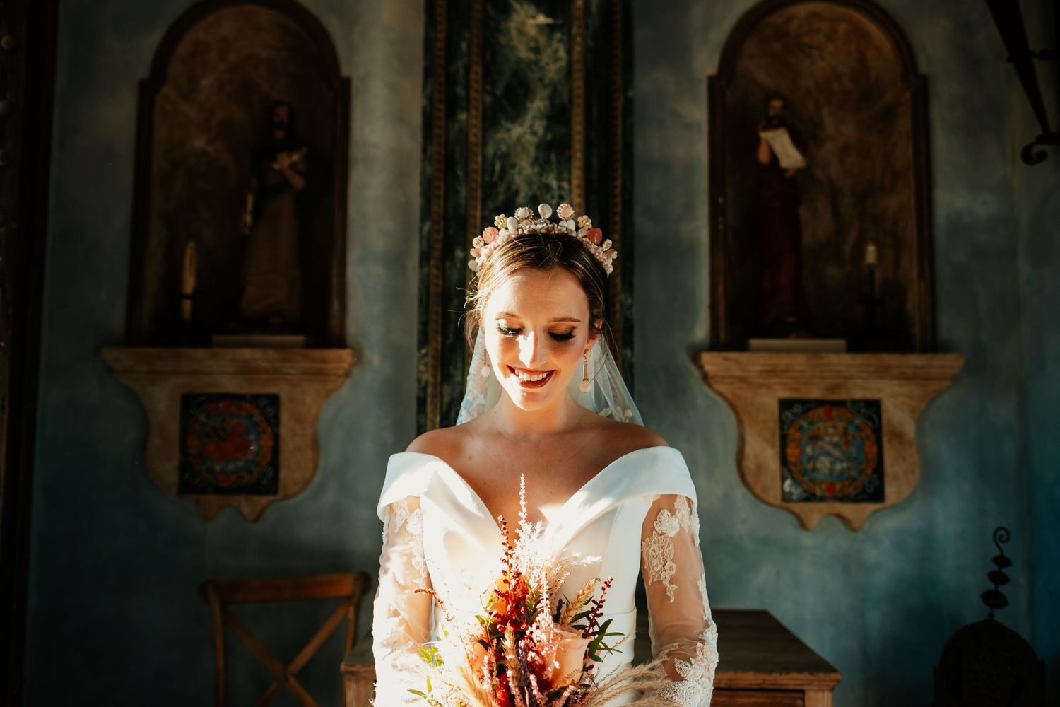 Elegant bride poses in ornate church interior holding dried flower bouquet.